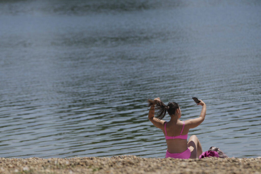 A girl takes a selfie at Ada Ciganlija lake in Belgrade, Serbia, Friday, June 20, 2025. (AP Photo/Darko Vojinovic)