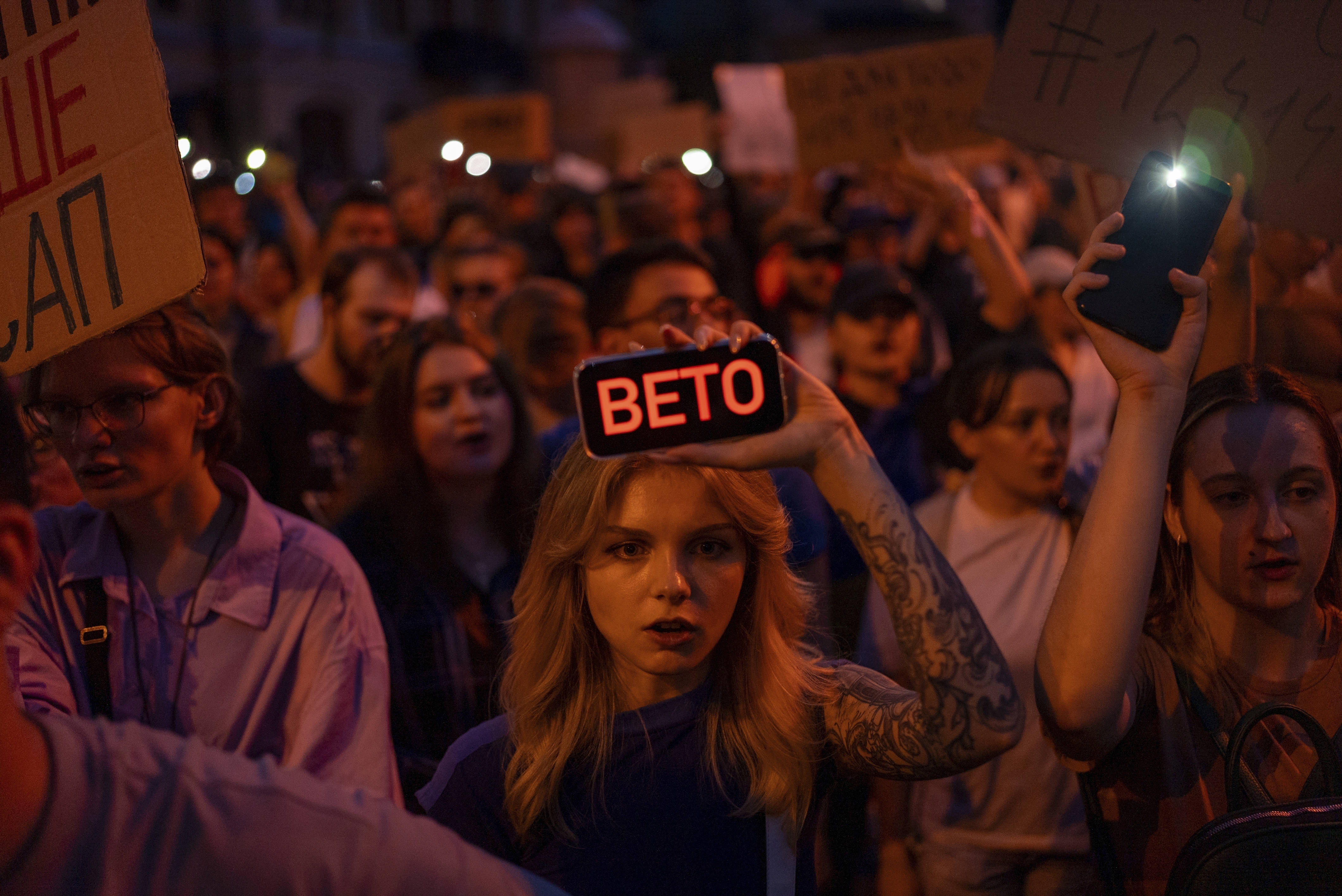 A woman holds a phone with a sign reads "Veto" during the protest against the law aimed towards regulations of anti-corruption institutions in central Kyiv, Ukraine, Tuesday, July 22, 2025. (AP Photo/Alex Babenko)