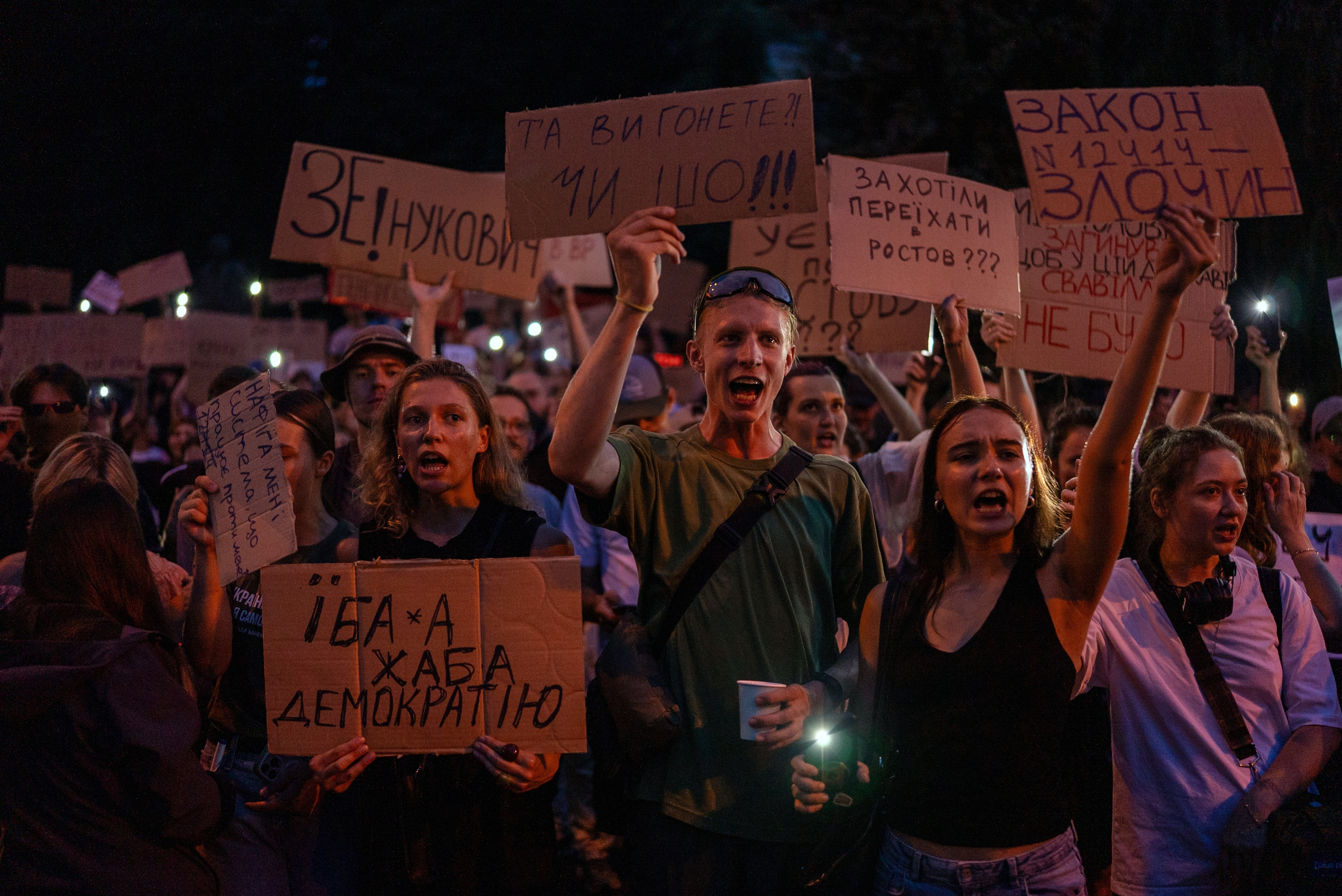 People chant while holding banners during a protest against a law targeting anti-corruption institutions in central Kyiv, Ukraine, Tuesday, July 22, 2025. (AP Photo/Alex Babenko)