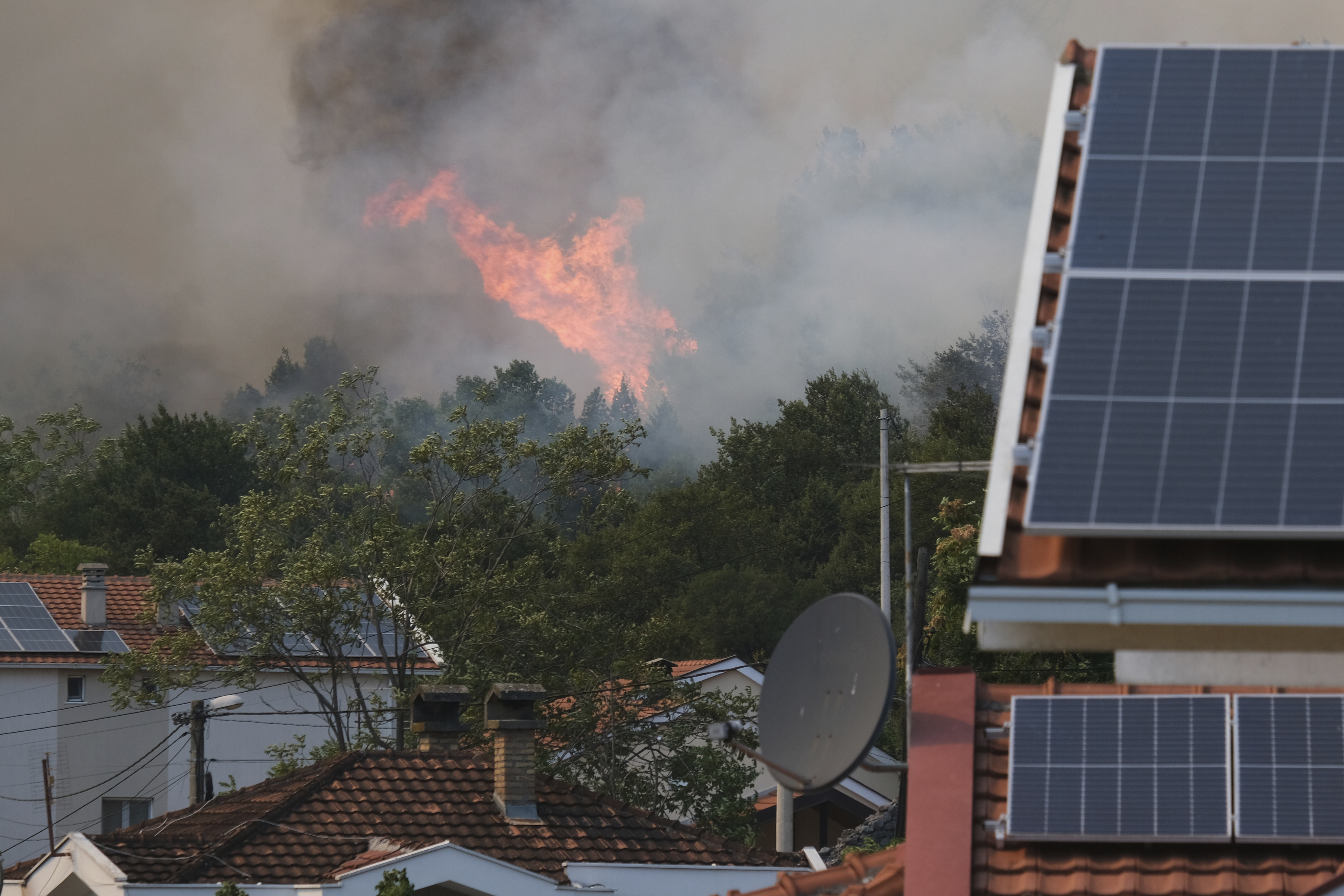 Smoke and flames rise from trees burning in a wildfire near Montenegro's capital of Podgorica, Monday, Aug. 11, 2025. (AP Photo/Risto Bozovic)