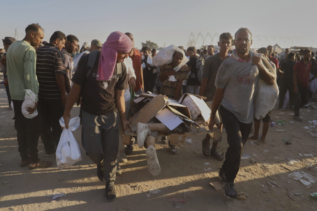 Palestinians carry the body of a woman who was hit by a truck while attempting to reach a humanitarian aid convoy moving along the Morag corridor near Rafah, in the southern Gaza Strip, Monday, Aug. 4, 2025. (AP Photo/Mariam Dagga)