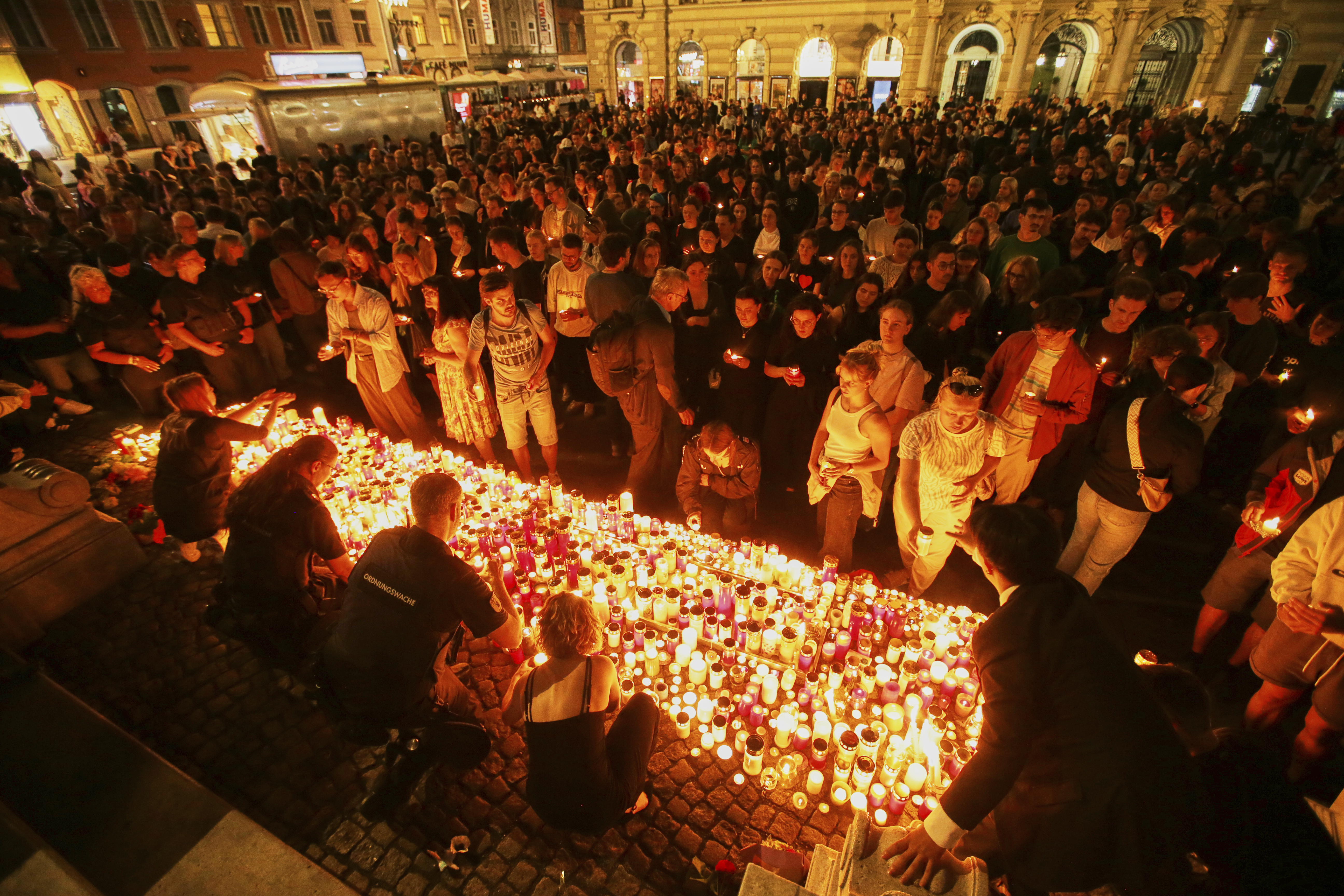 People light candles on the main square in the city center after a deadly shooting at a school in Graz, Austria, Tuesday, June 10, 2025. (AP Photo/Heinz-Peter Bader)