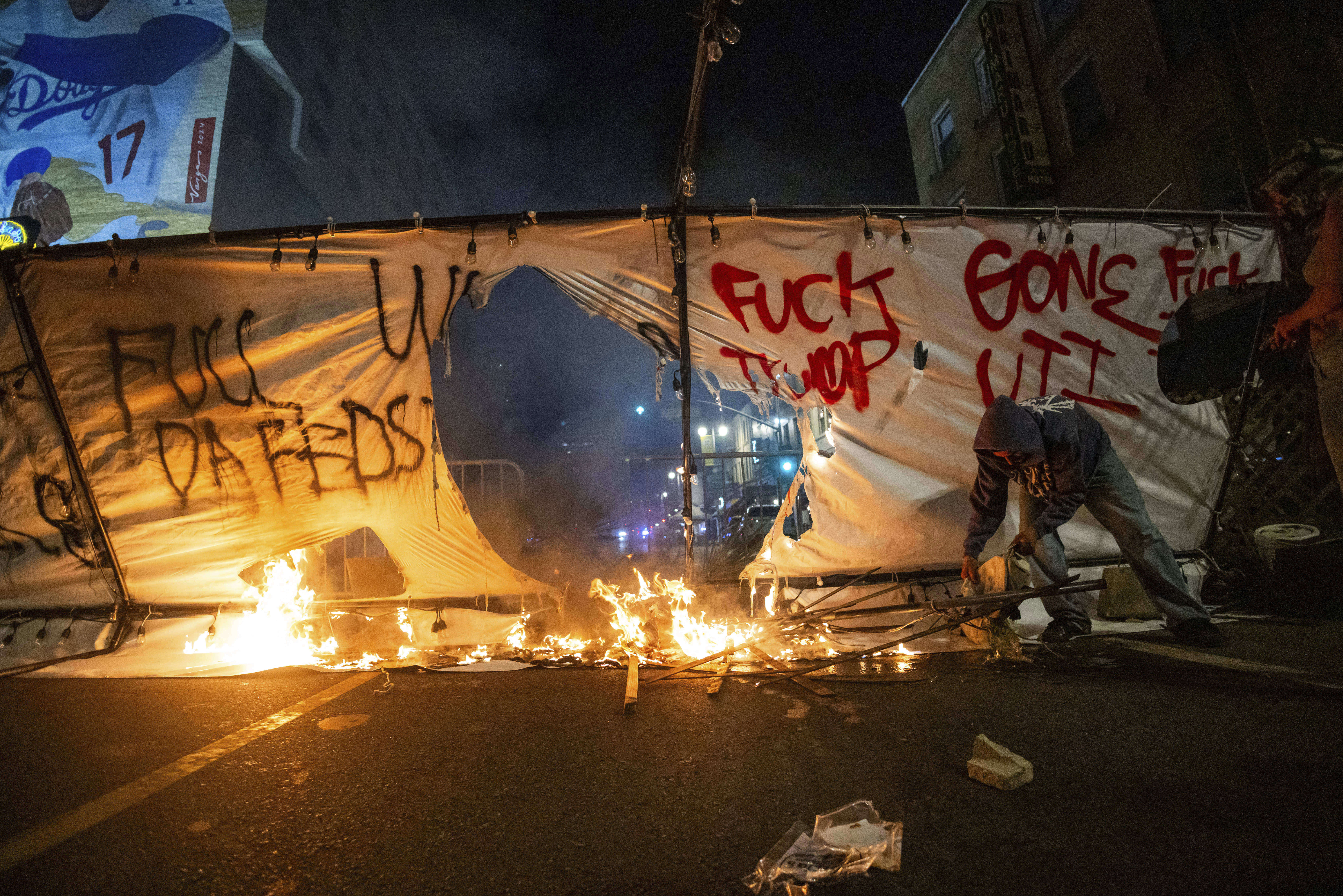 EDS NOTE: OBSCENITY - A protestor sets a fire during protests over the Trump administration's immigration raids in Los Angeles, Monday, June 9, 2025. (AP Photo/Ethan Swope)