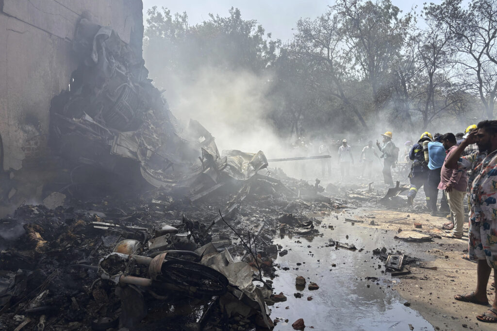 People stand around debris at the site of an airplane that crashed in India's northwestern city of Ahmedabad in Gujarat state, Thursday, June12, 2025. (AP Photo/Ajit Solanki)