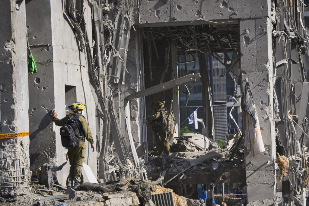 Rescue workers and military personnel inspect the site of a direct hit from an Iranian missile strike in Ramat Gan, Israel, Thursday, June 19, 2025. (AP Photo/Oded Balilty)