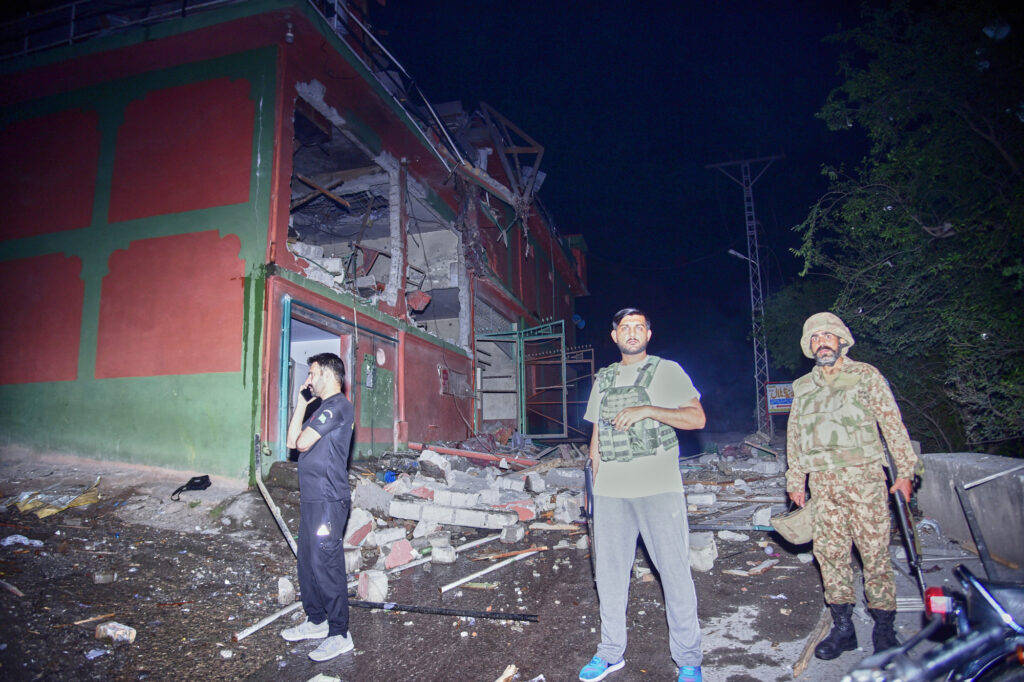 Security force officials stand outside a damaged building at a site of a suspected Indian missile attack near Muzaffarabad, the capital of Pakistan controlled Kashmir, in Wednesday, May 7, 2025. (AP Photo/M.D. Mughal)