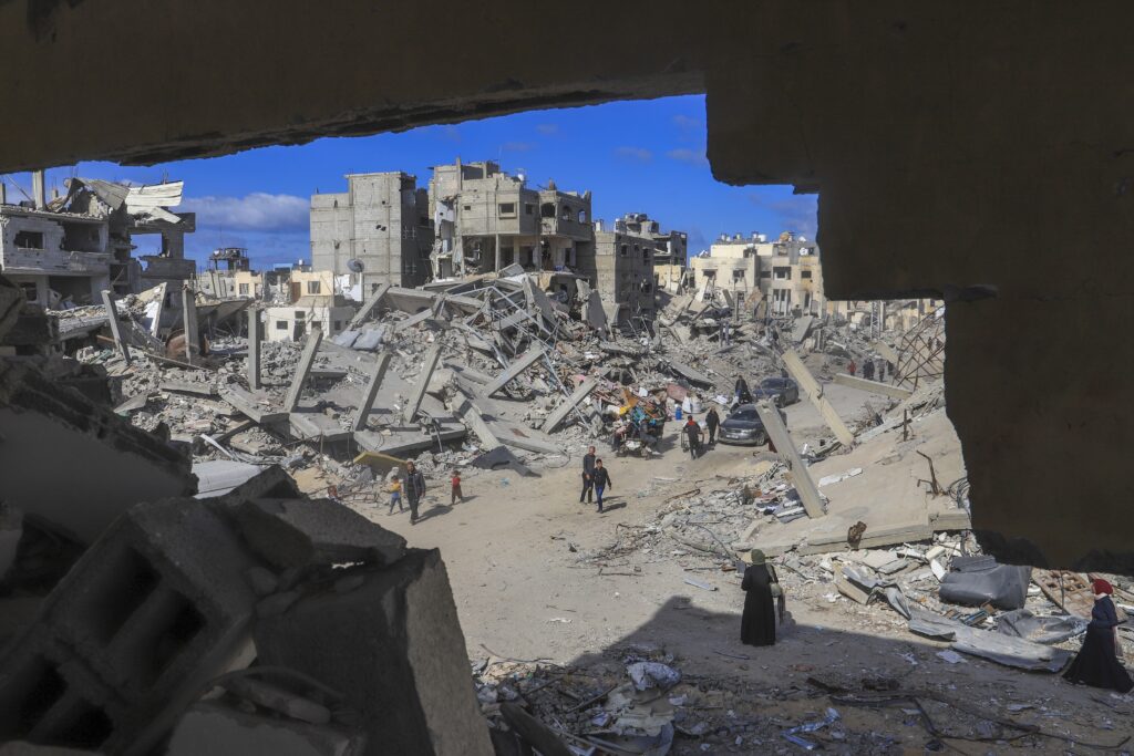 Palestinians walk through the rubble caused by the Israeli air and ground offensive in Rafah, southern Gaza Strip, Monday, Jan. 20, 2025. (AP Photo/Mariam Dagga)