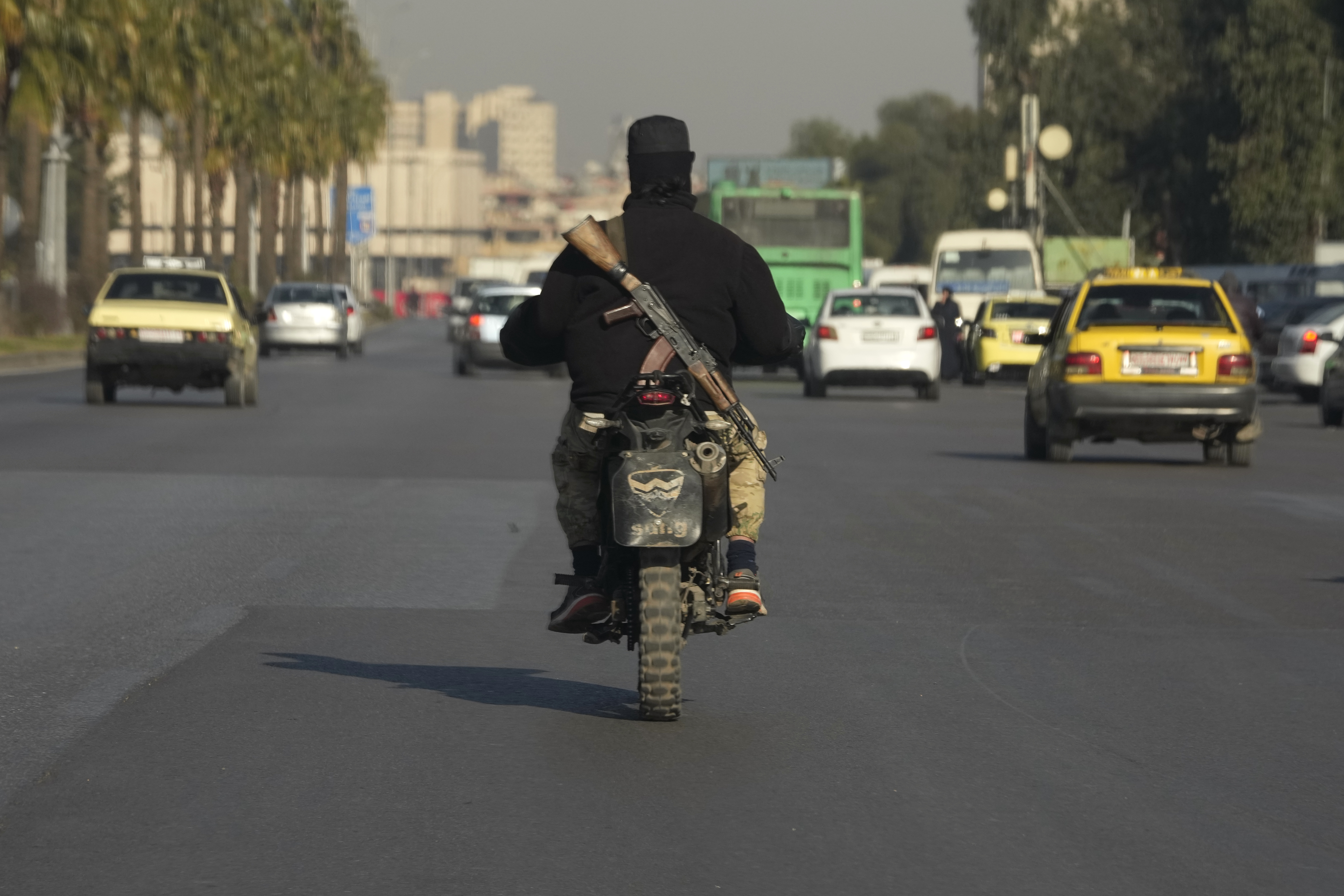 A Syrian fighter rides his motorcycle along a highway in Damascus, Syria,  Wednesday, Dec. 18, 2024.  (AP Photo/Hussein Malla)