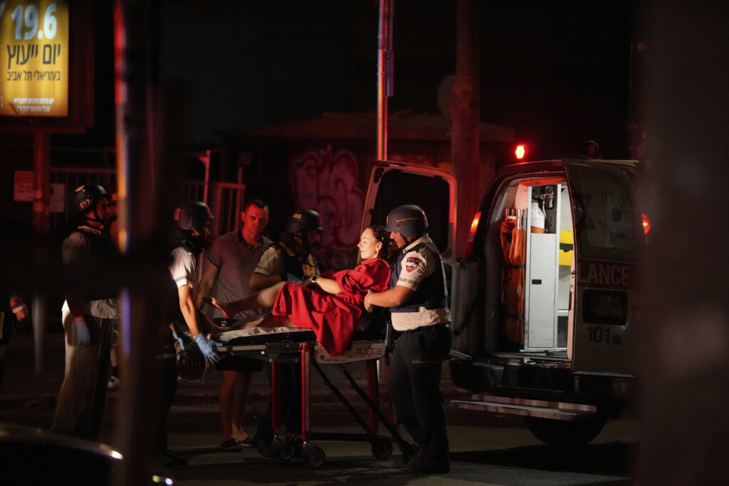 Paramedics evacuate a wounded woman from a building struck by a missile fired from Iran, in Tel Aviv, Israel, on Friday, June 13, 2025. (AP Photo/Tomer Appelbaum)