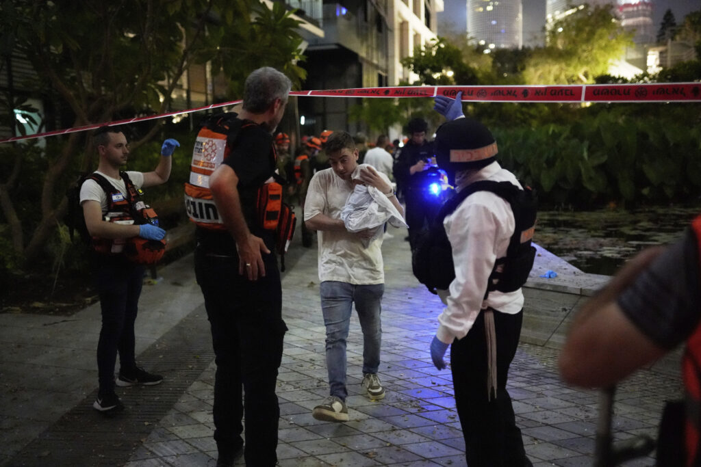 People evacuate from a building struck by a missile fired from Iran, in Tel Aviv, Israel, on Friday, June 13, 2025. (AP Photo/Tomer Appelbaum)