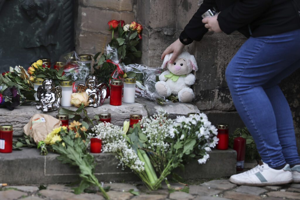 A woman lays down a cuddly toy at the memorial site at St. John's Church in Magdeburg, Germany, Saturday Dec. 21, 2024, the morning after a driver drove into a group of people at Magdeburg's Christmas market. (Jan Woitas/dpa via AP)