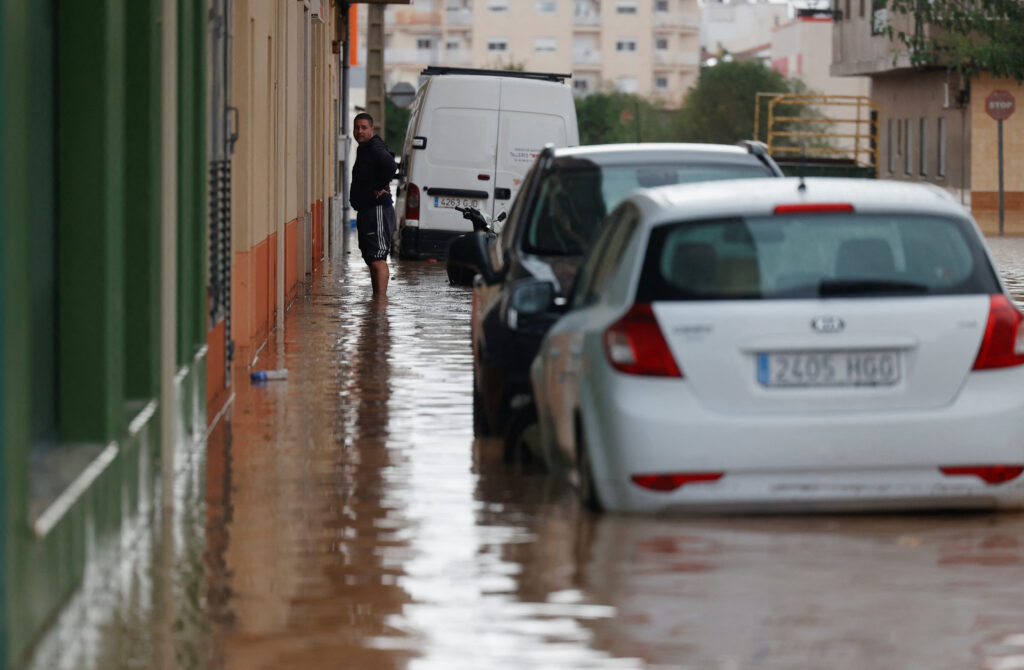 A person stands in a flooded street after the Spanish meteorological agency put the Valencia region in the highest red alert for extreme rainfalls, in Catadau, Valencia, Spain, October 29, 2024. REUTERS/Eva Manez