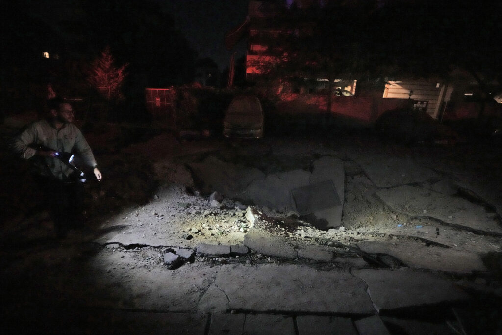 A man walks past a crater at the site of an Israeli airstrike in Beirut's southern suburbs Friday, Sept. 27, 2024. (AP Photo/Bilal Hussein)
