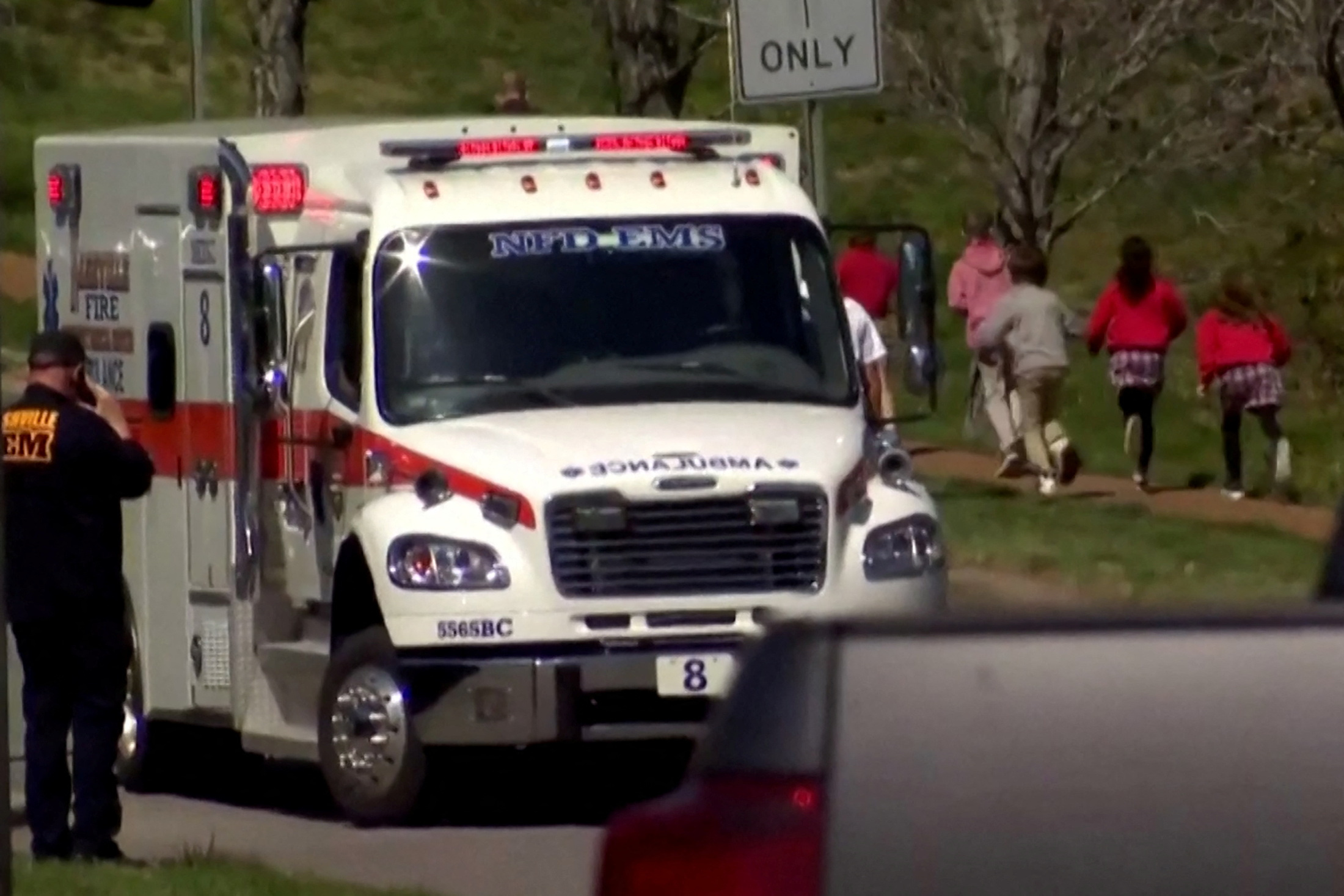 Children run past an ambulance near the Covenant School after a shooting in Nashville, Tennessee, U.S. March 27, 2023 in a still image from video.  WKRN/NewsNation via REUTERS.  NO RESALES. NO ARCHIVES MANDATORY CREDIT