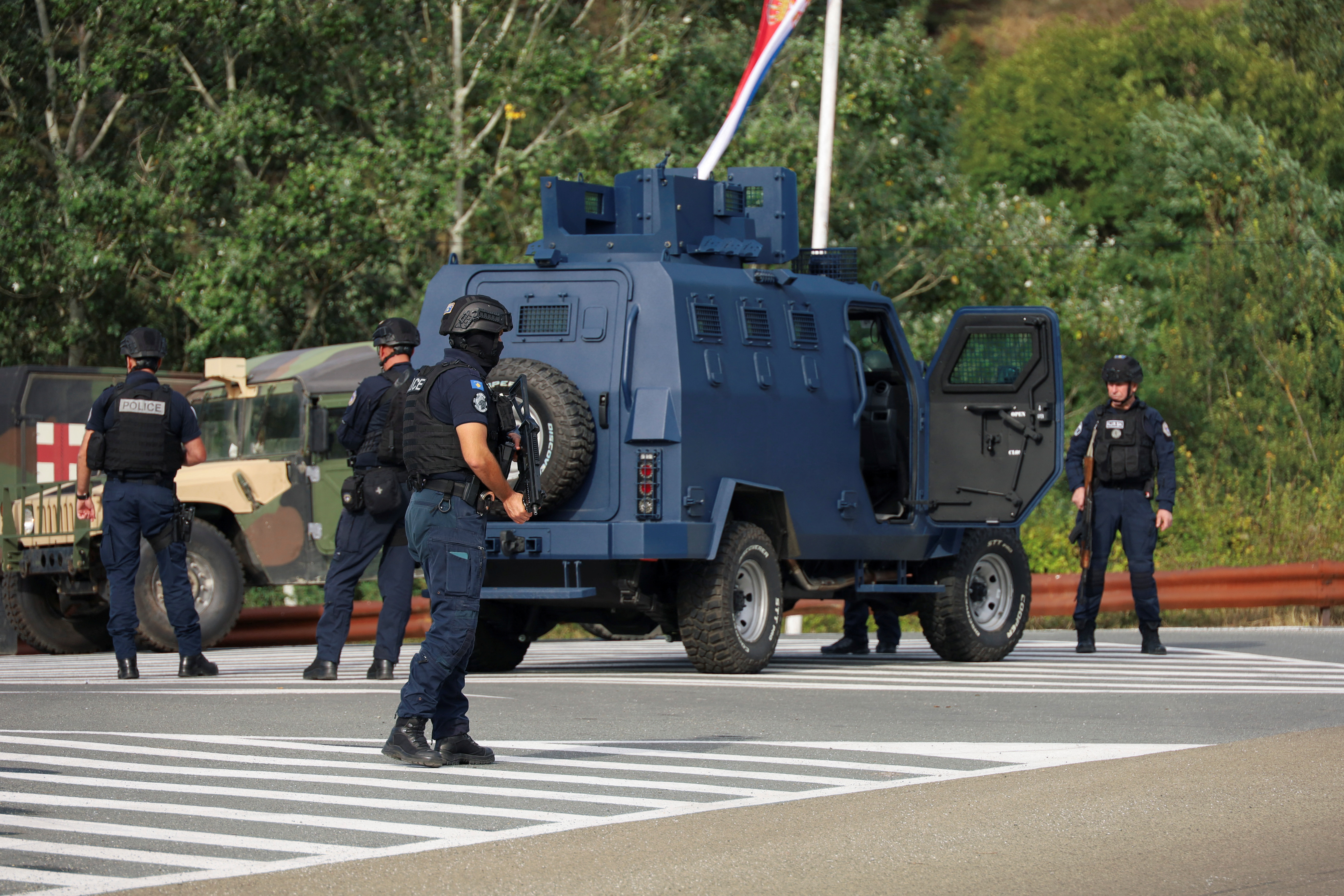 People work as Kosovo police and U.S. and EU troops stand by after one police officer was killed, another hurt in Kosovo gunfire, in Josevik, Kosovo September 24, 2023. REUTERS/Fatos Bytyci