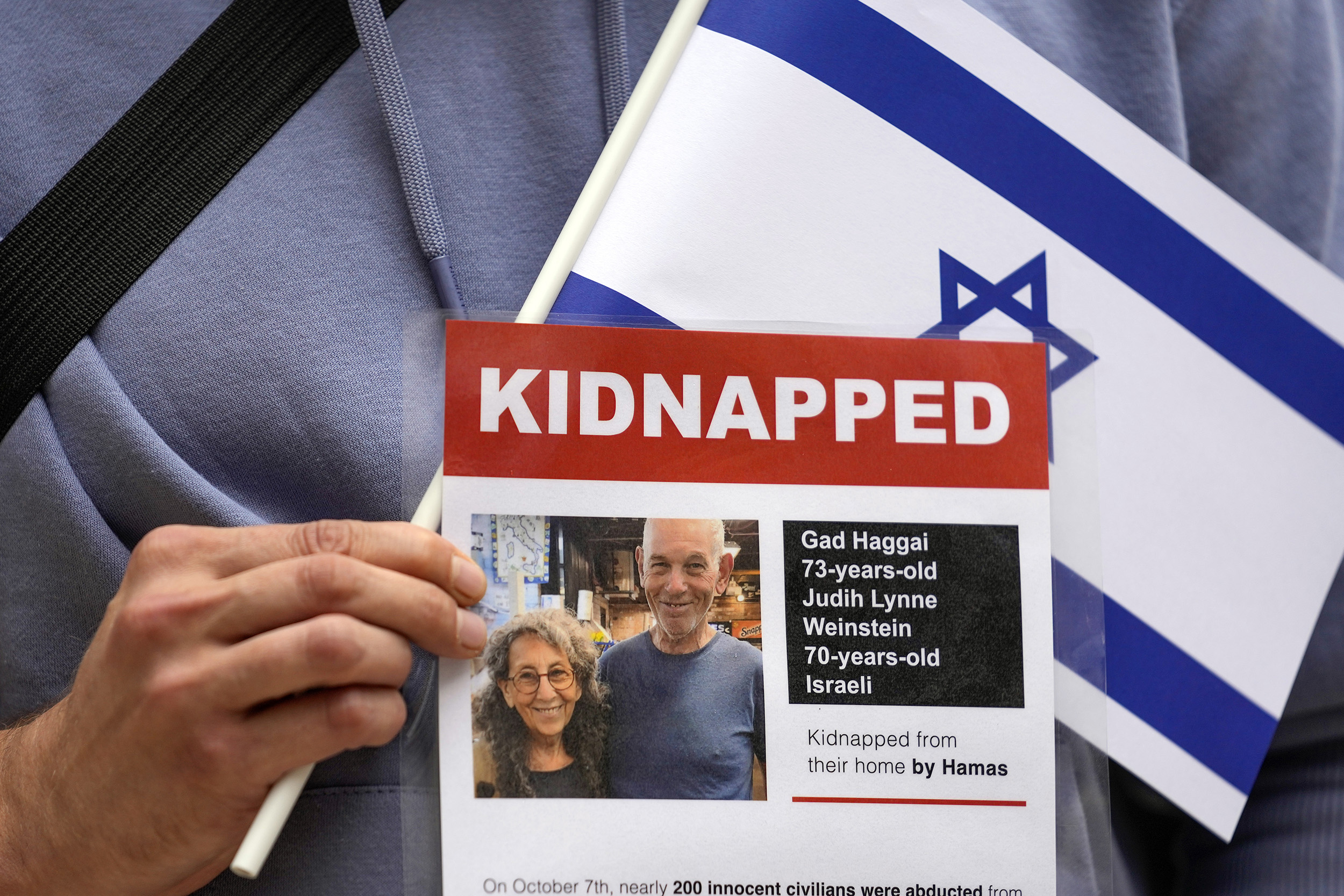 A man holds an Israeli flag and a poster during a peace rally against war between Israel and Hamas in Belgrade, Serbia, Sunday, Oct. 15, 2023. (AP Photo/Darko Vojinovic)