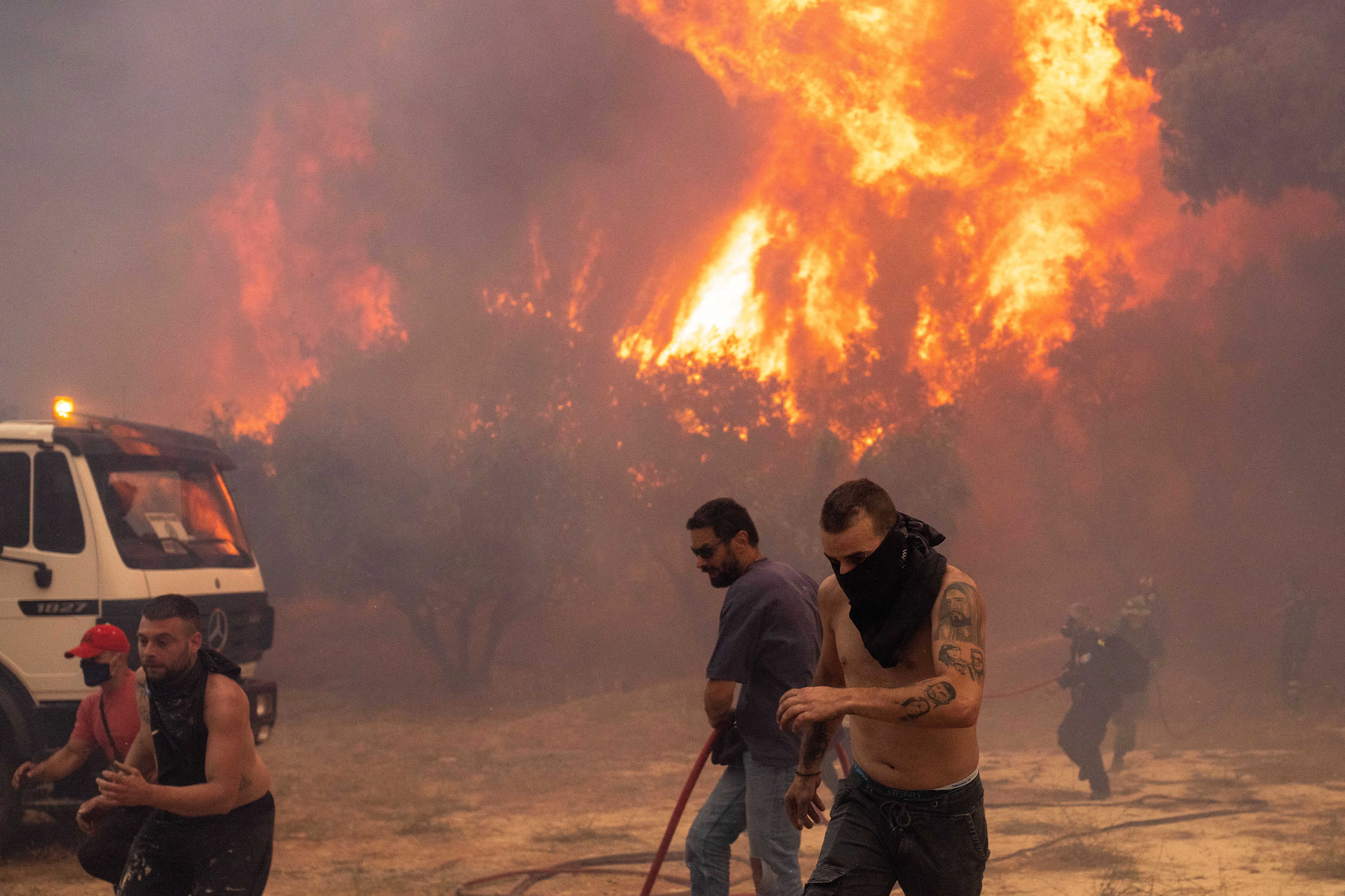 Firefighters and volunteers flee as a wildfire burns in the village of Hasia, near Athens, Greece August 22, 2023. REUTERS/Alkis Konstantinidis