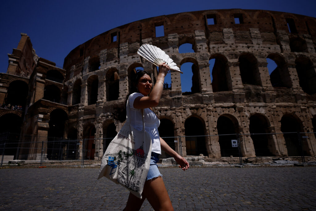 Michelle from the U.S. uses a fan to shelter from the sun near the Colosseum during a heatwave across Italy, in Rome, Italy July 11, 2023. REUTERS/Guglielmo Mangiapne