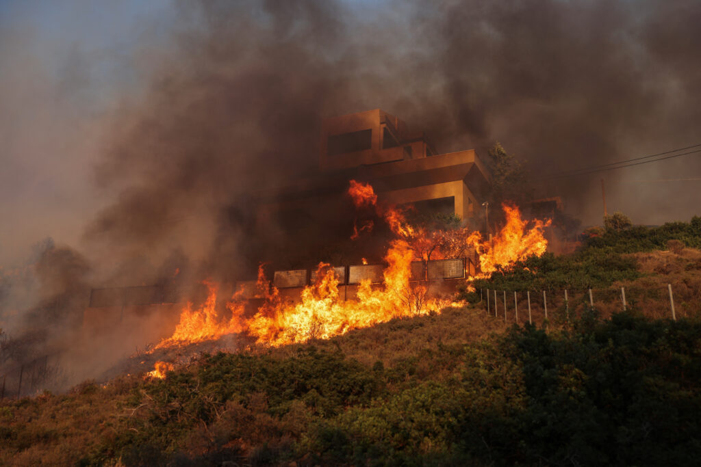 Flames engulf a house as a wildfire burns in Saronida, near Athens, Greece, July 17, 2023. REUTERS/Stelios Misinas