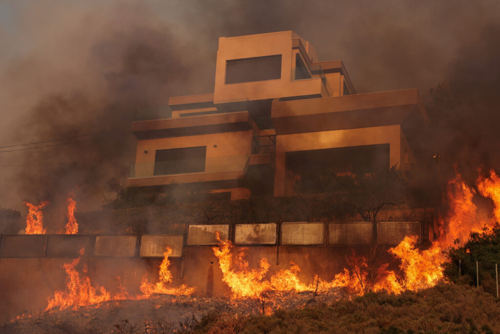 Flames engulf a house as a wildfire burns in Saronida, near Athens, Greece, July 17, 2023. REUTERS/Stelios Misinas