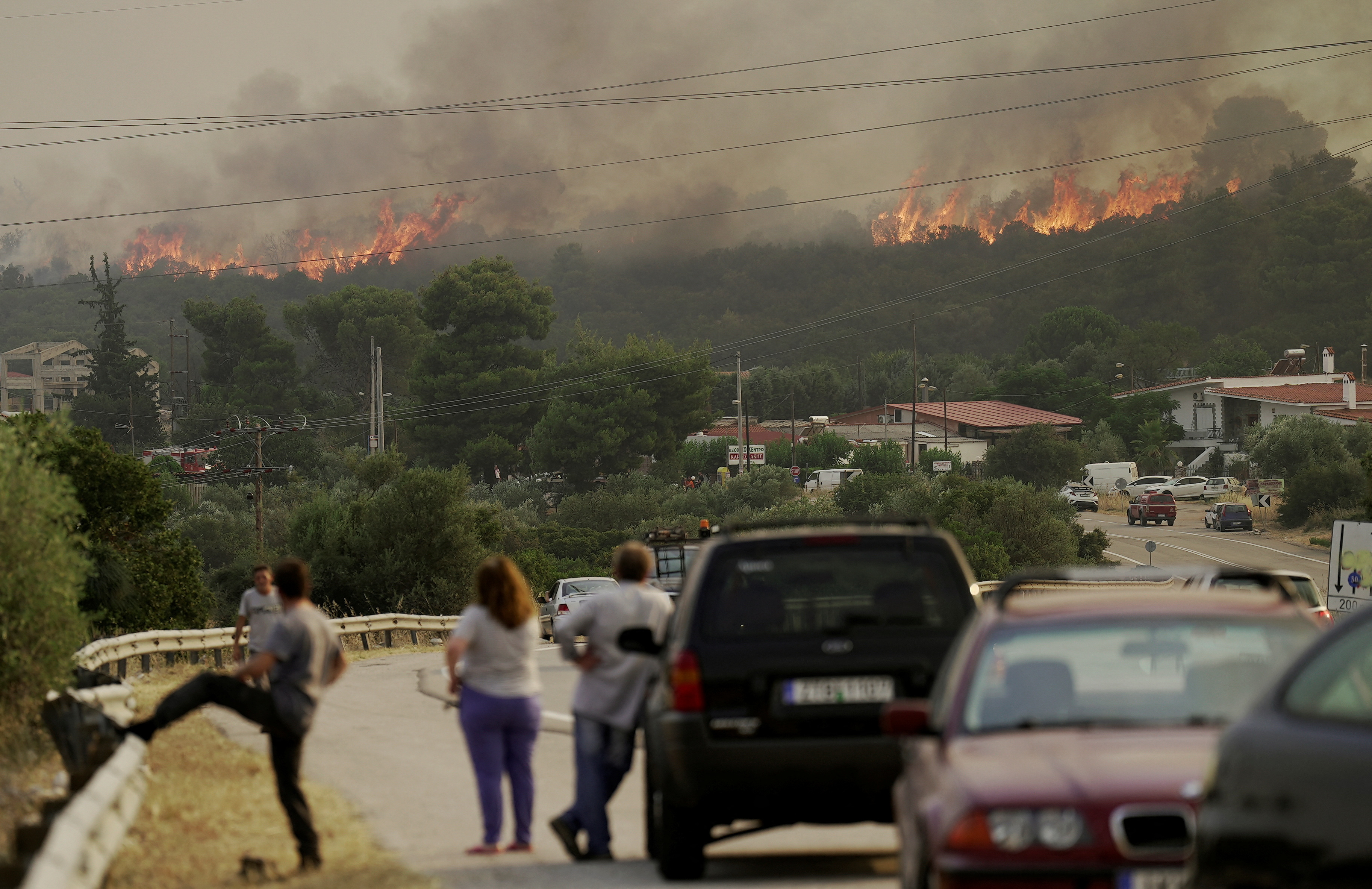 People gather as wildfire burns near the village of Agios Sotira, west of Athens, Greece, July 20, 2023. REUTERS/Fedja Grulovic