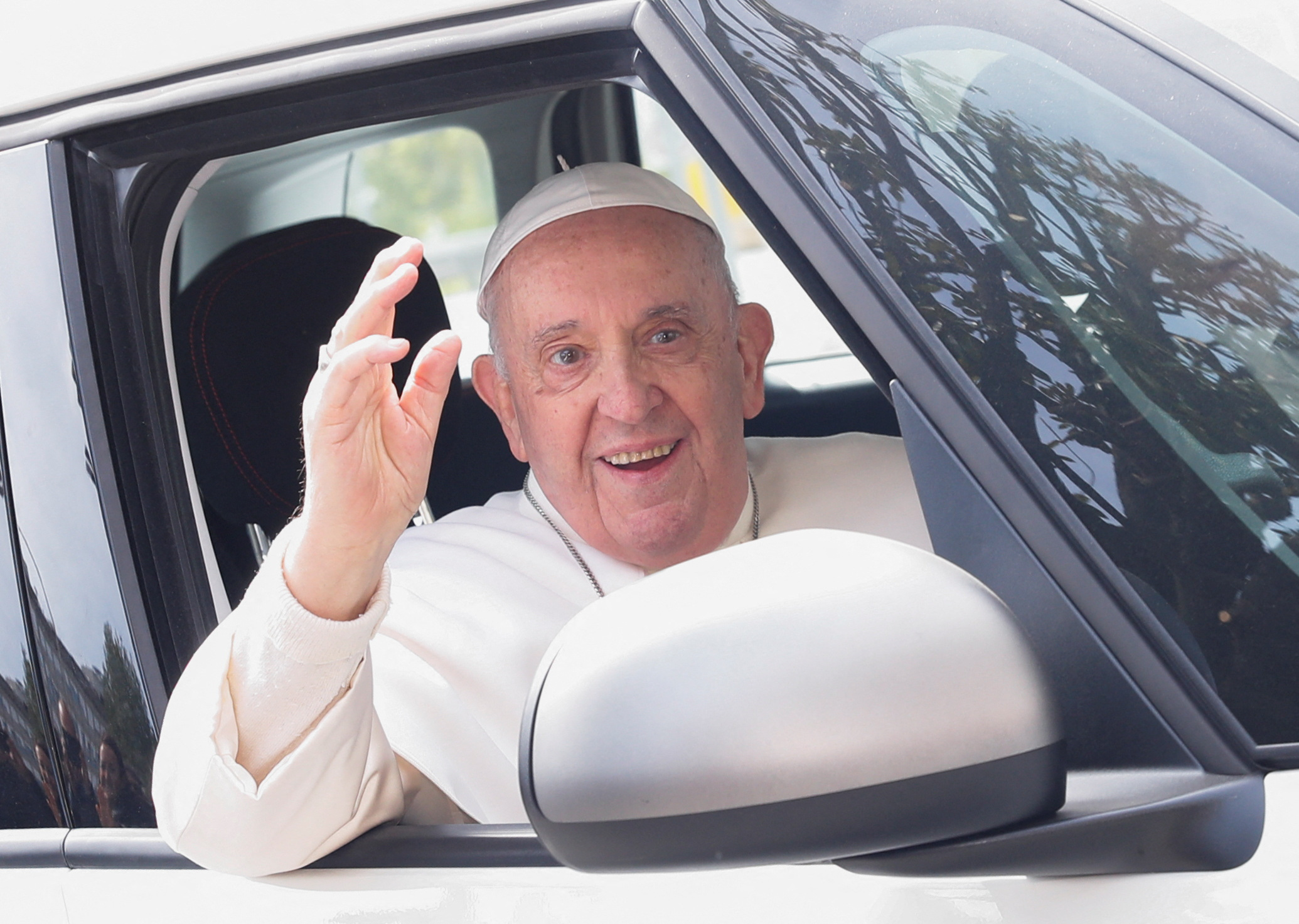Pope Francis waves from a car as he leaves Rome's Gemelli hospital in Rome