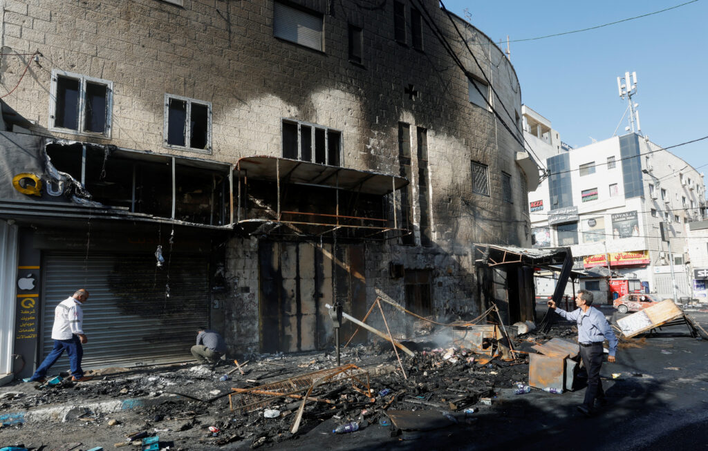 People walk past debris and a building damaged amid an Israeli military operation, in Jenin, in the Israeli-occupied West Bank July 4, 2023. REUTERS/Mohamad Torokman