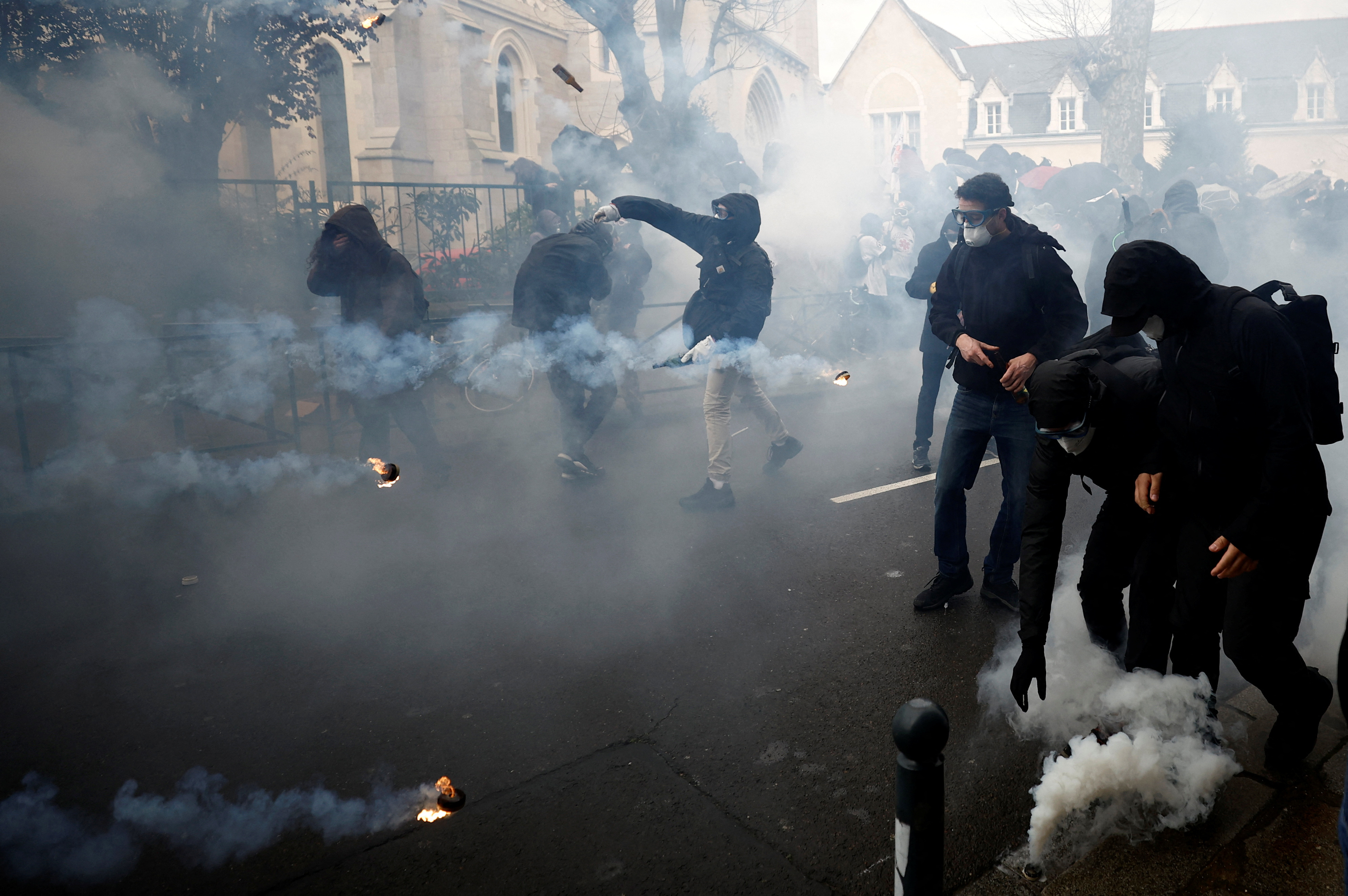 Masked protesters react amid tear gas during clashes at a demonstration as part of the eleventh day of nationwide strikes and protests against French government's pension reform, in Rennes, France, April 6, 2023.  REUTERS/Stephane Mahe