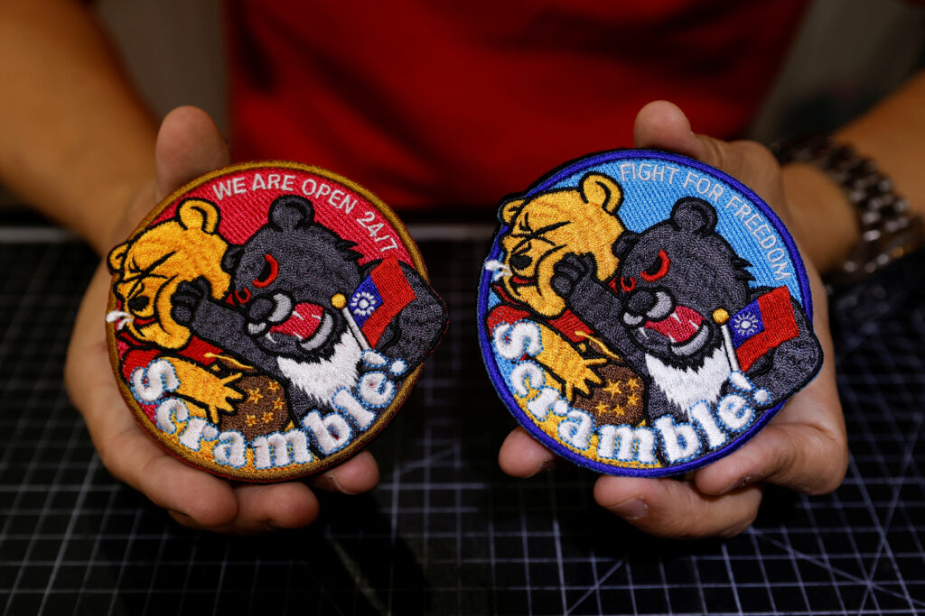 Alec Hsu shows to the camera patches depicting a Formosan black bear holding Taiwan’s flag and punching Winnie the Pooh at his store in Taoyuan, Taiwan April 10, 2023. REUTERS/Carlos Garcia Rawlins
