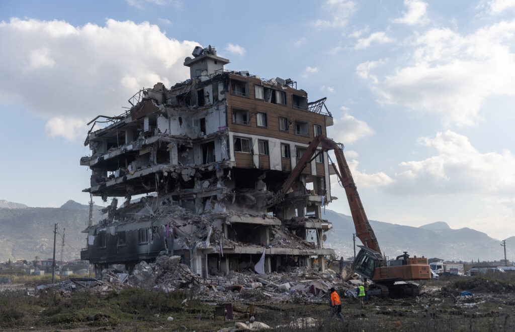 A construction vehicle takes apart a damaged building, in the aftermath of a deadly earthquake in Hatay, Turkey, February 19, 2023. REUTERS/Maxim Shemetov