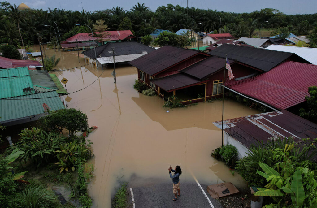 A person takes pictures of a flooding residential area in Yong Peng, Johor, Malaysia, March 4, 2023. REUTERS/Hasnoor Hussain