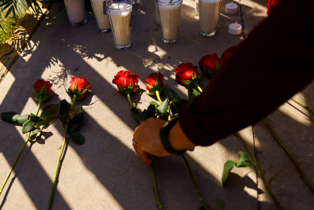 A person places flowers next to candles during a protest outside the National Institute of Migration building after a fire broke out late on Monday at a migrant detention center, in Ciudad Juarez, Mexico, March 28, 2023. REUTERS/Jose Luis Gonzalez