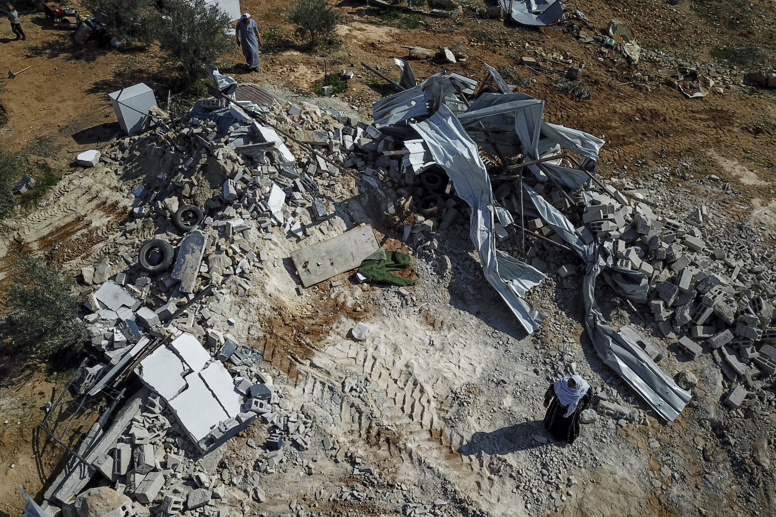 Palestinian women gather beside the rubble of their house that was demolished by Israeli authorities at Khirbet Ma'in in the area of Masafer Yatta, south of the West Bank city of Hebron, Wednesday, Jan. 25, 2023. (AP Photo/Sam McNeil)