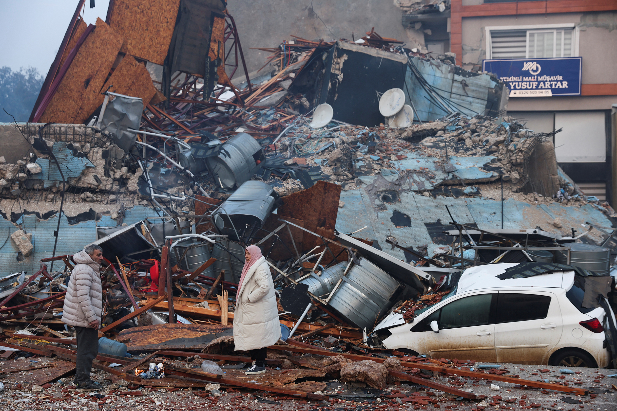 People look at rubble and damage following an earthquake in Hatay, Turkey, February 7, 2023. REUTERS/Umit Bektas