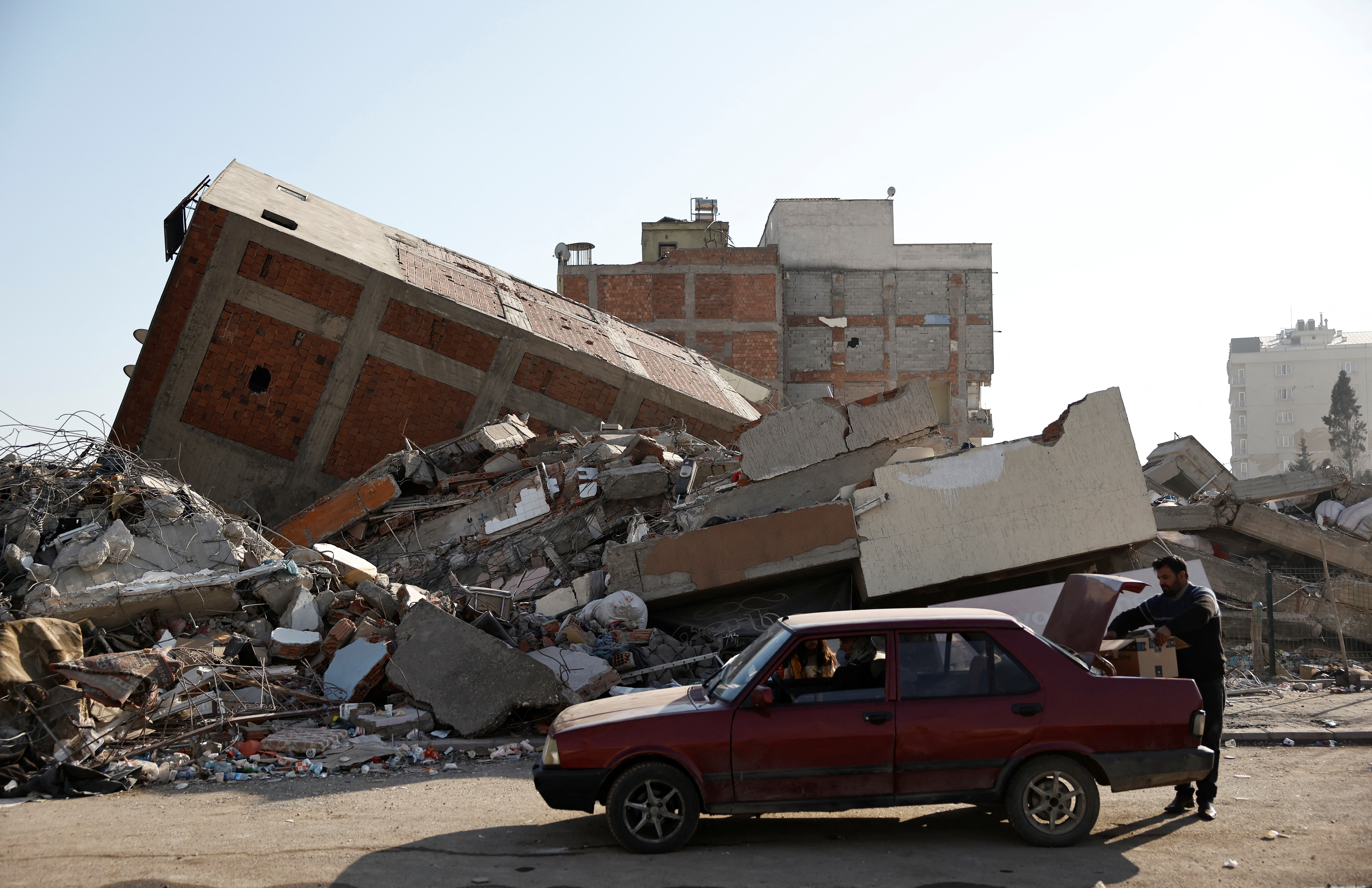 A family park their car in front of what used to be their home and collect personal belongings they retrieved from the rubble, in the aftermath of a deadly earthquake, in Kahramanmaras, Turkey, February 18, 2023. REUTERS/Clodagh Kilcoyne