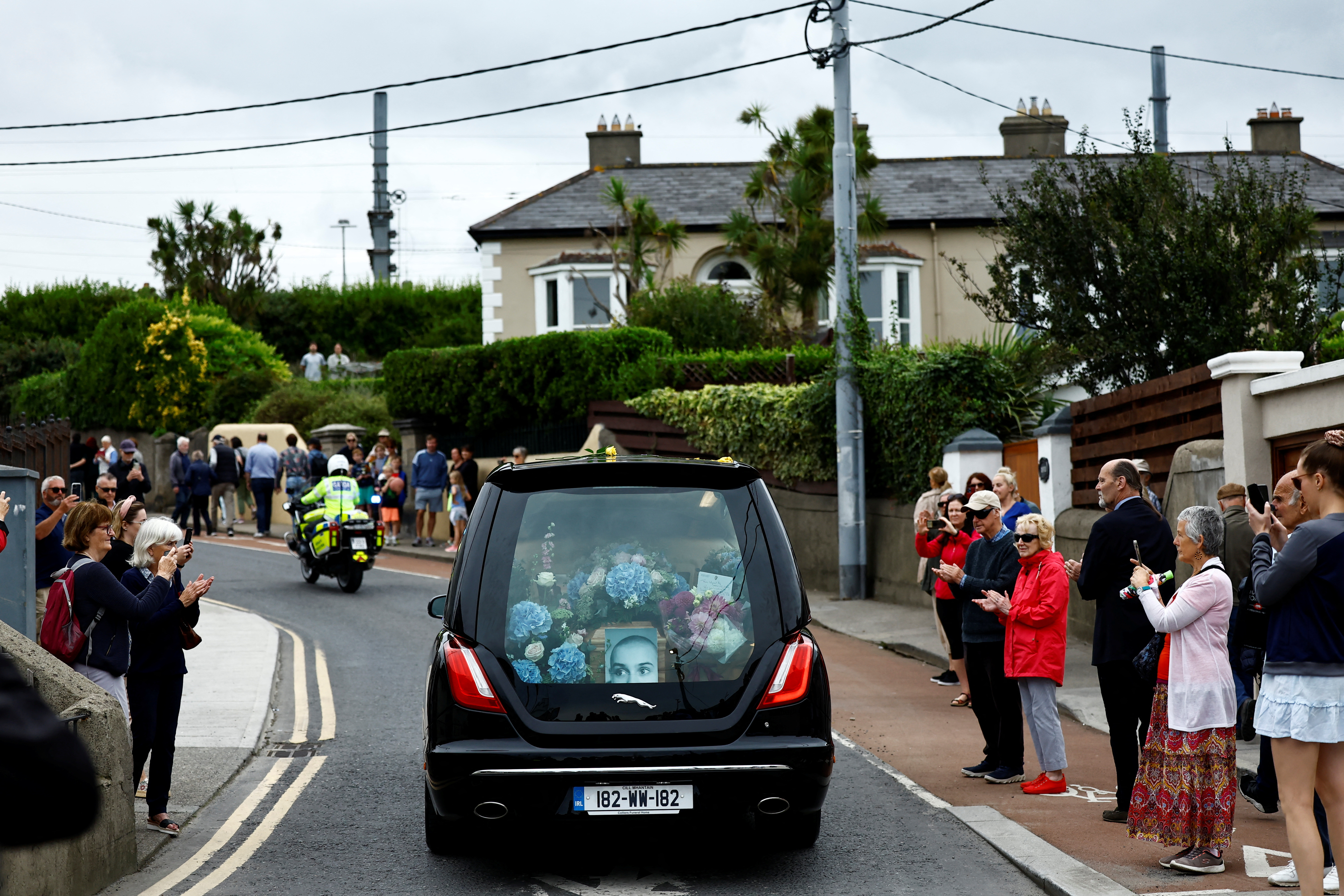 A hearse carrying the coffin of late Irish singer Sinead O'Connor passes near her former home during her funeral procession as fans line the street to say their last goodbye to her, in Bray, Ireland, August 8, 2023. REUTERS/Clodagh Kilcoyne