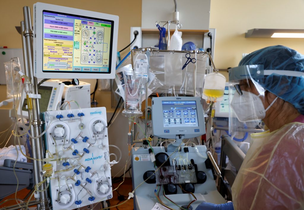 A nurse in a protective suit treats a patient suffering from the coronavirus disease (COVID-19) with a new CRP-Apherese treatment in the Intensive Care Unit (ICU) at Havelhoehe community hospital in Berlin, Germany, April 9, 2021. REUTERS/Fabrizio Bensch