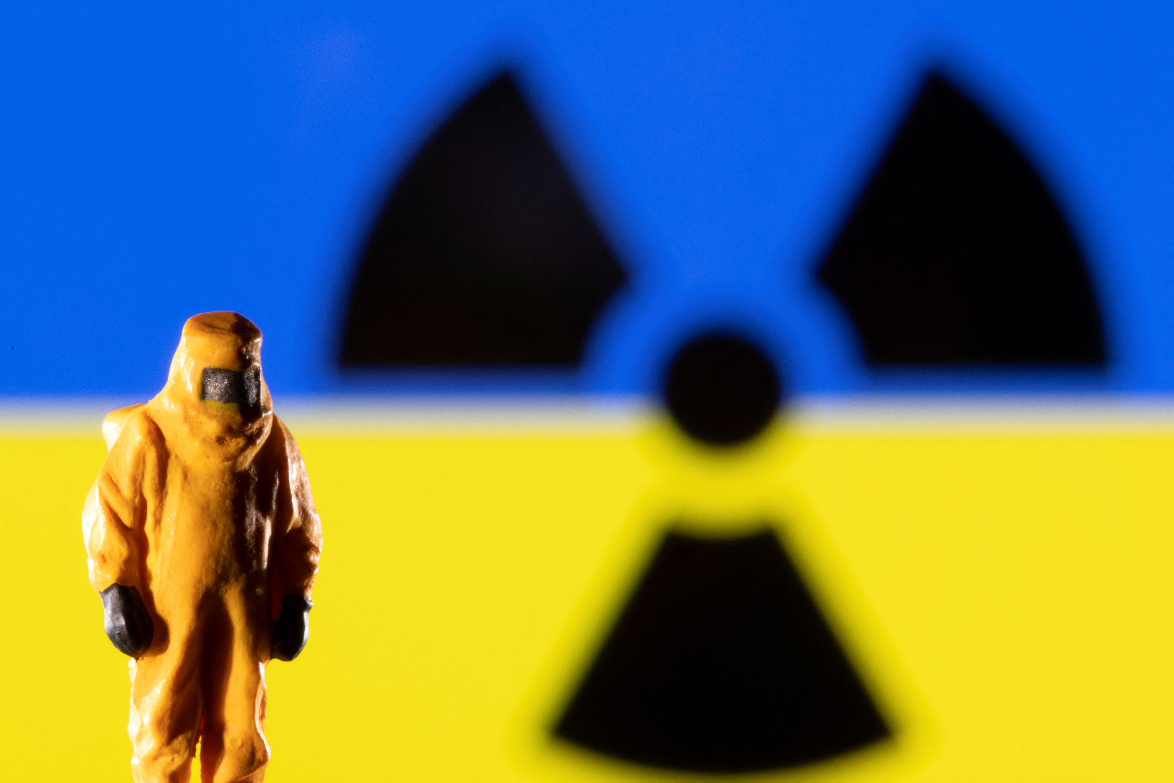 A figurine in protective equipment is seen in front of a displayed Ukrainian flag and a Radiation sign in this illustration taken March 9, 2022. REUTERS/Dado Ruvic/Illustration