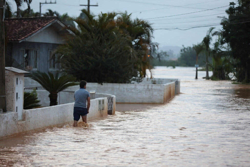 A man walks through a flooded street after heavy rains in Canelinha, in Santa Catarina state, Brazil, December 1, 2022. REUTERS/Anderson Coelho NO RESALES. NO ARCHIVES.