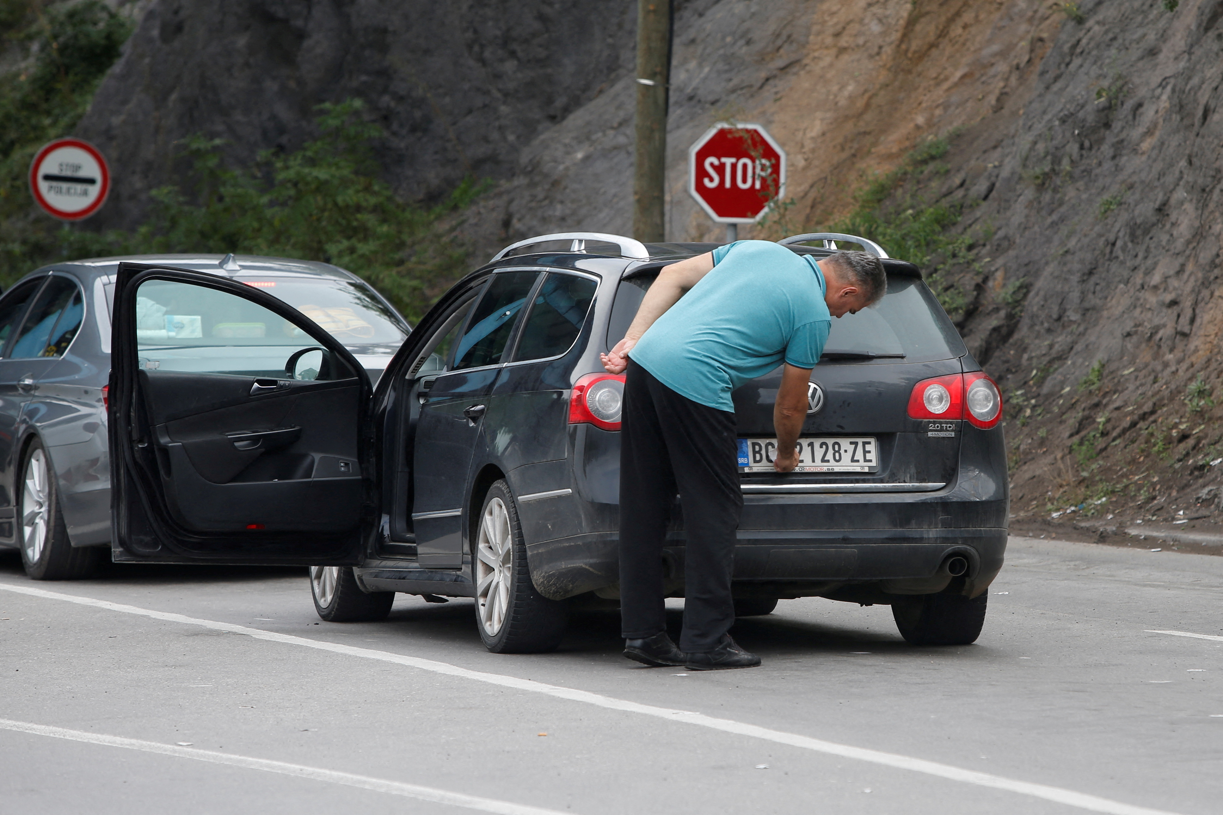 FILE PHOTO: A driver removes a sticker covering the national markings on his car plates at the Jarinje border crossing, Kosovo September 1, 2022. REUTERS/Ognen Teofilovski/File Photo