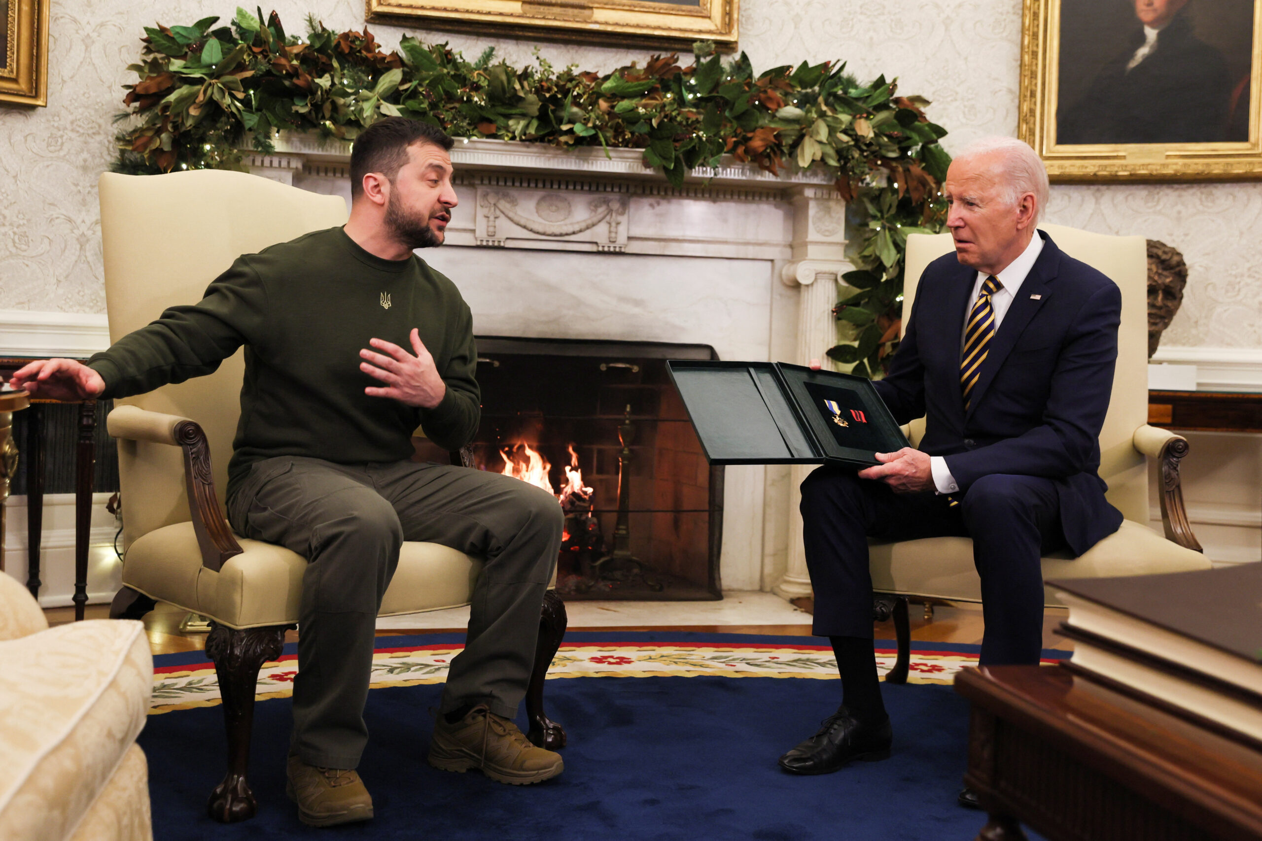 Ukraine's President Volodymyr Zelenskiy delivers a soldier's gift to U.S. President Joe Biden in the Oval Office at the White House in Washington, U.S., December 21, 2022. REUTERS/Leah Millis