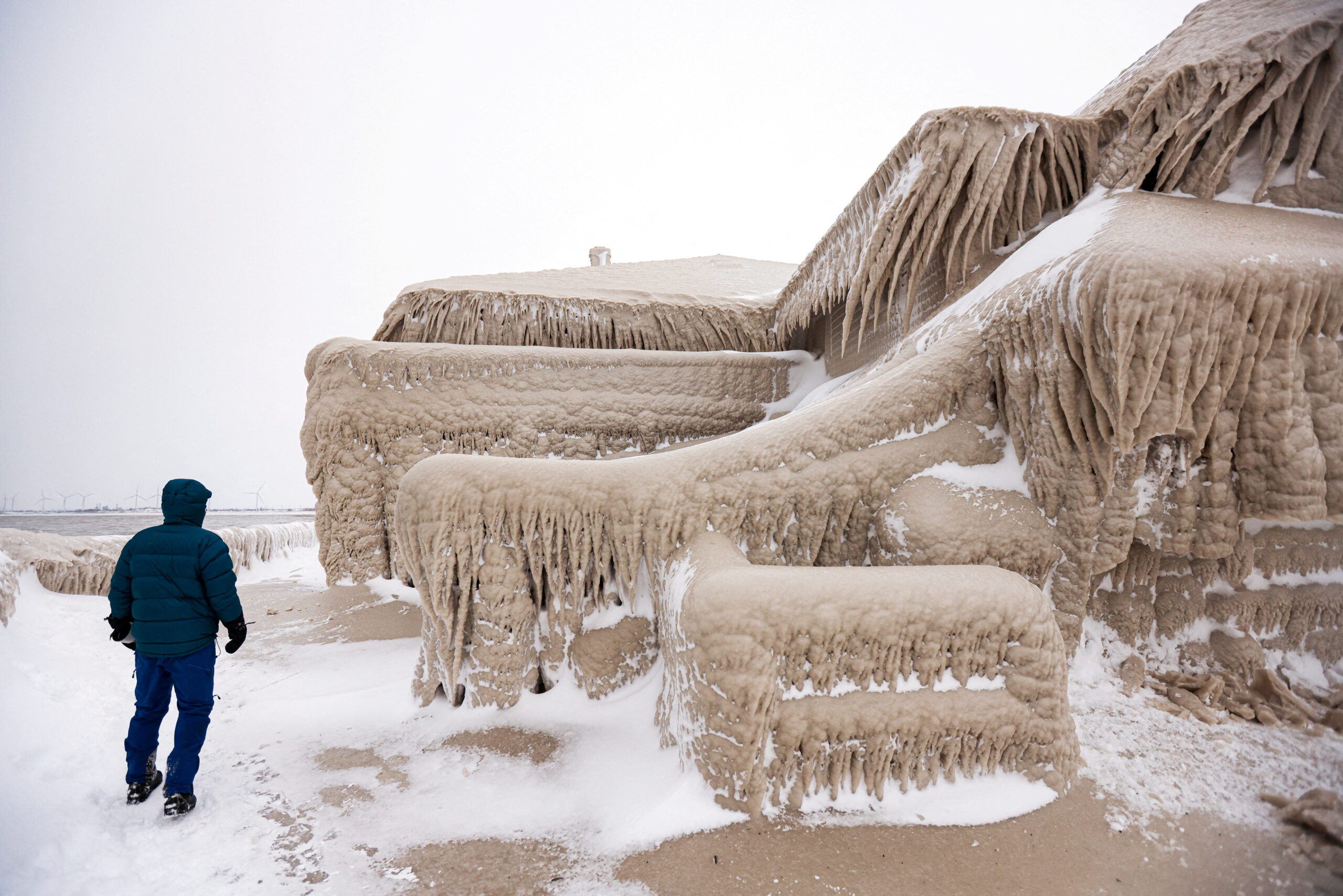 sneg i led u SAD  A man walks beside ice formed by the spray of Lake Erie waves which covered a restaurant during a winter storm in Hamburg, New York, U.S., December 26, 2022.  REUTERS/Lindsey DeDario     TPX IMAGES OF THE DAY