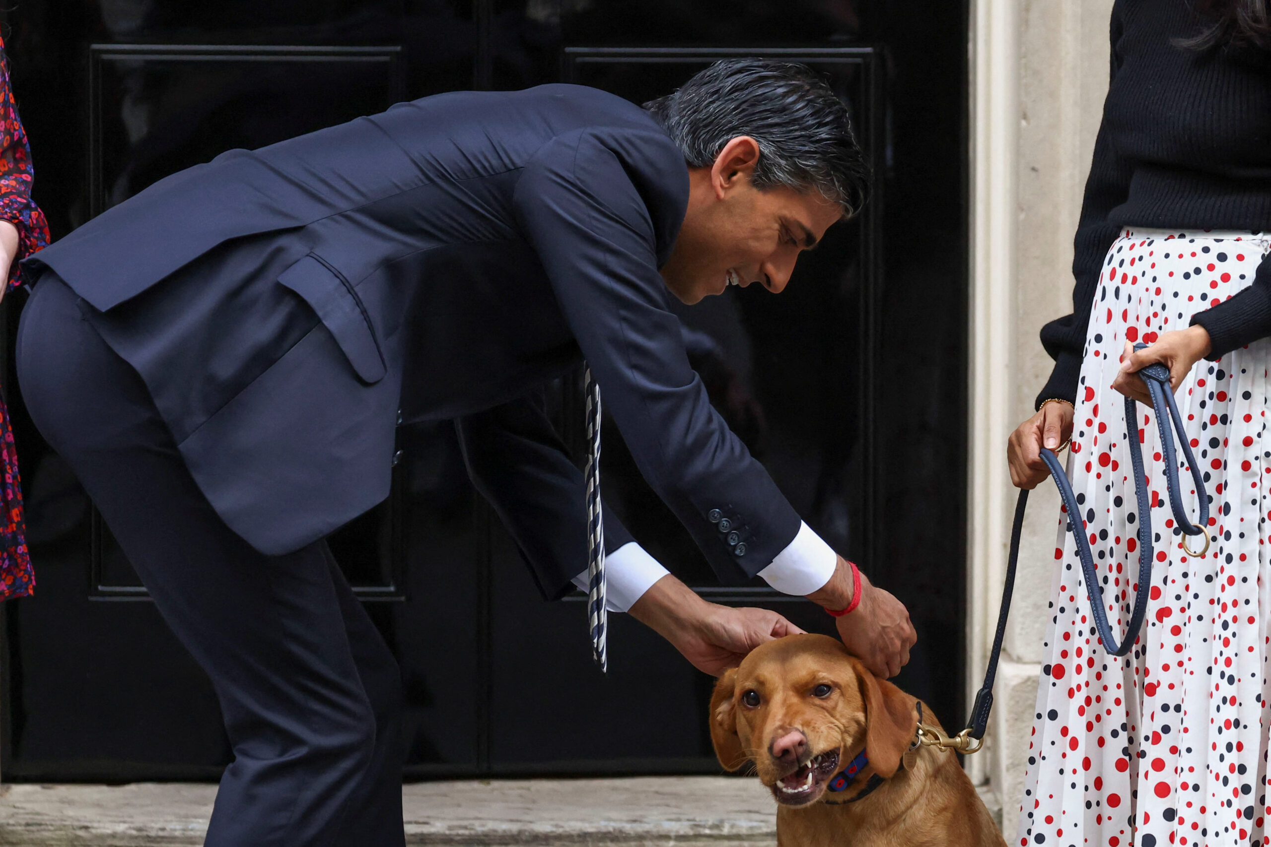 British Prime Minister Rishi Sunak tends to his dog Nova, next to his wife Akshata Murty, as they meet volunteers from the Royal British Legion outside Number 10 Downing Street in London, Britain, October 31, 2022. REUTERS/Henry Nicholls