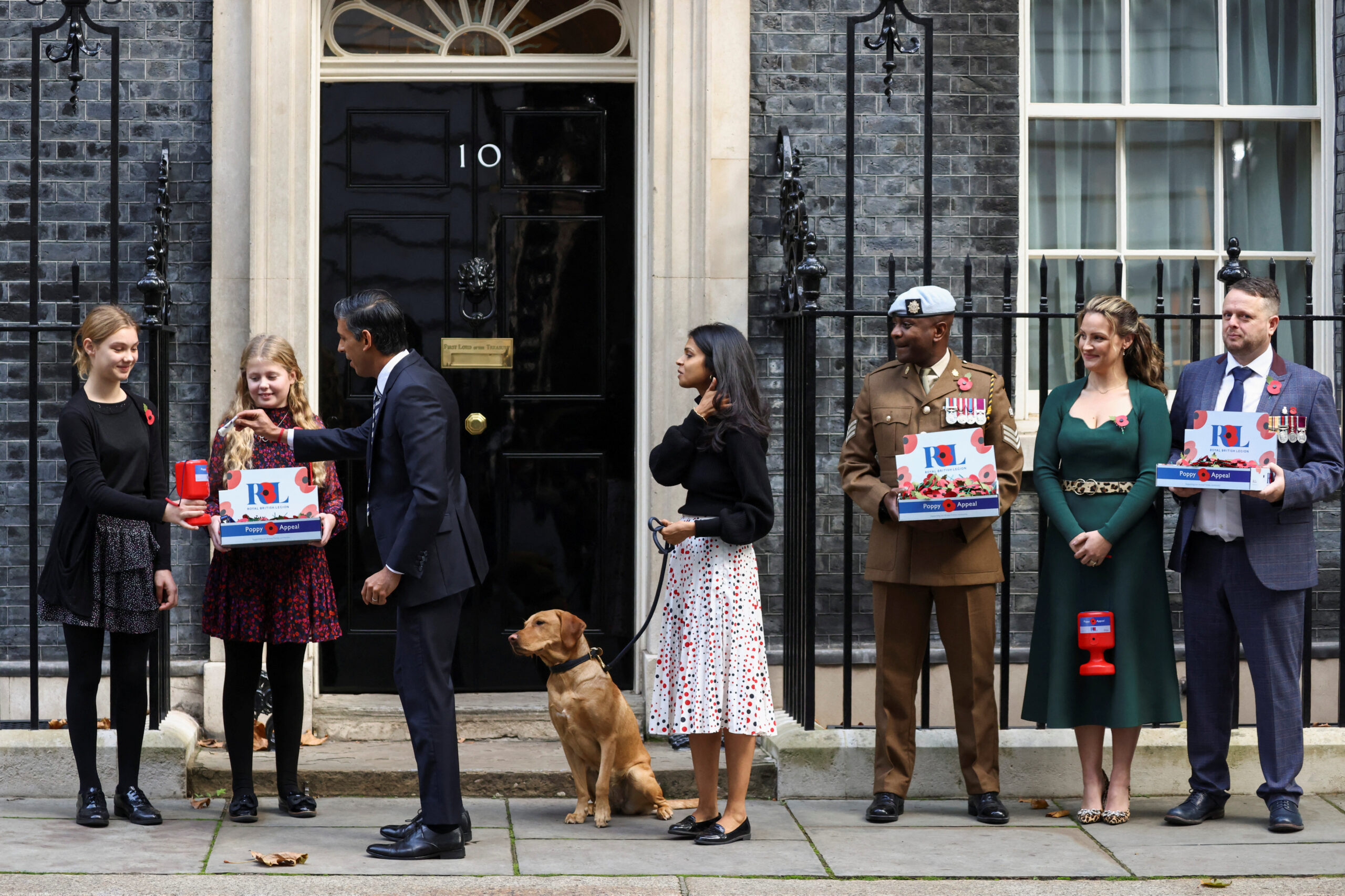 British Prime Minister Rishi Sunak purchases a poppy pin from Royal British Legion fundraisers next to his wife Akshata Murty and dog Nova, outside Number 10 Downing Street in London, Britain, October 31, 2022. REUTERS/Henry Nicholls