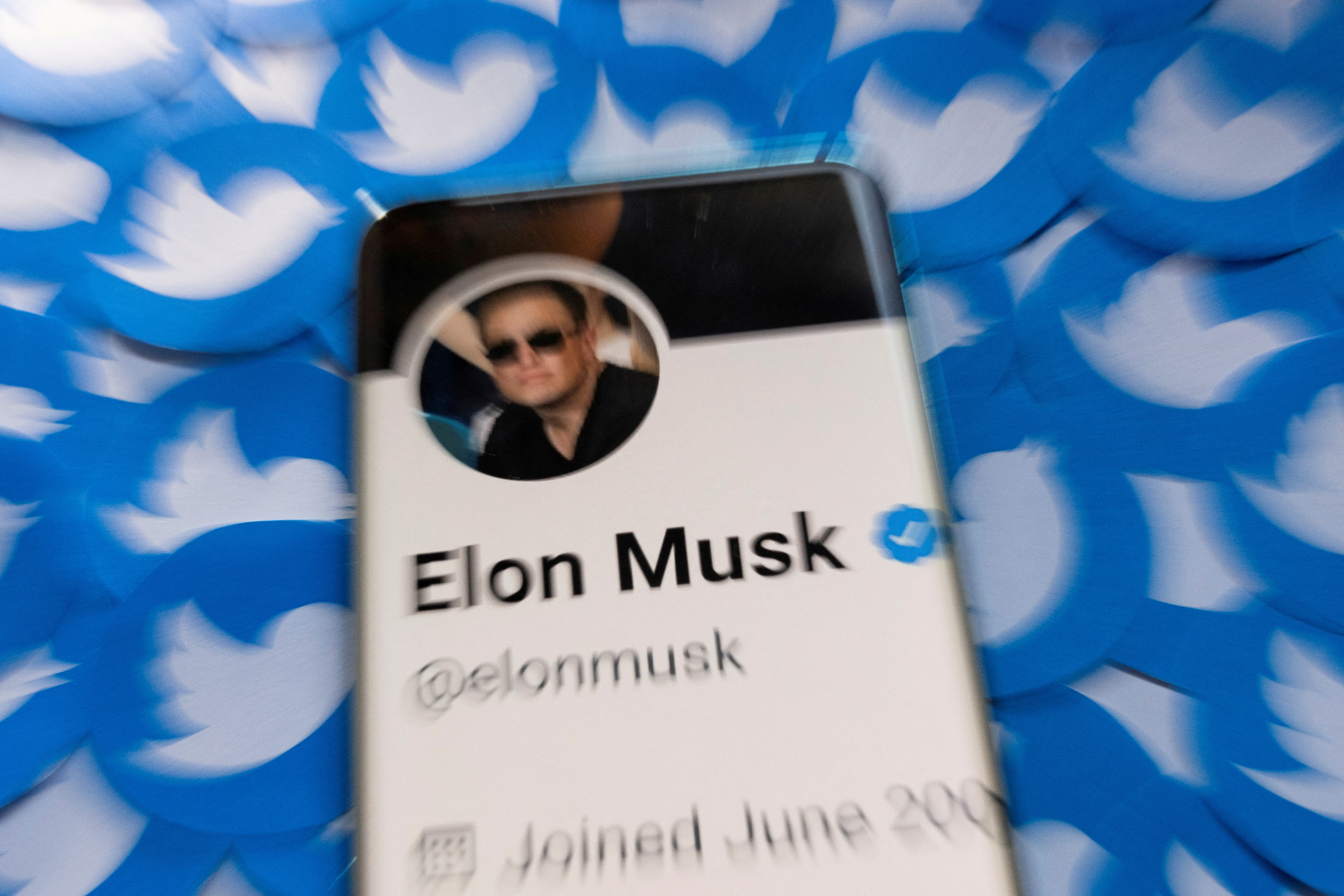 FILE PHOTO: Illustration shows Elon Musk's Twitter profile on smartphone and printed Twitter logos