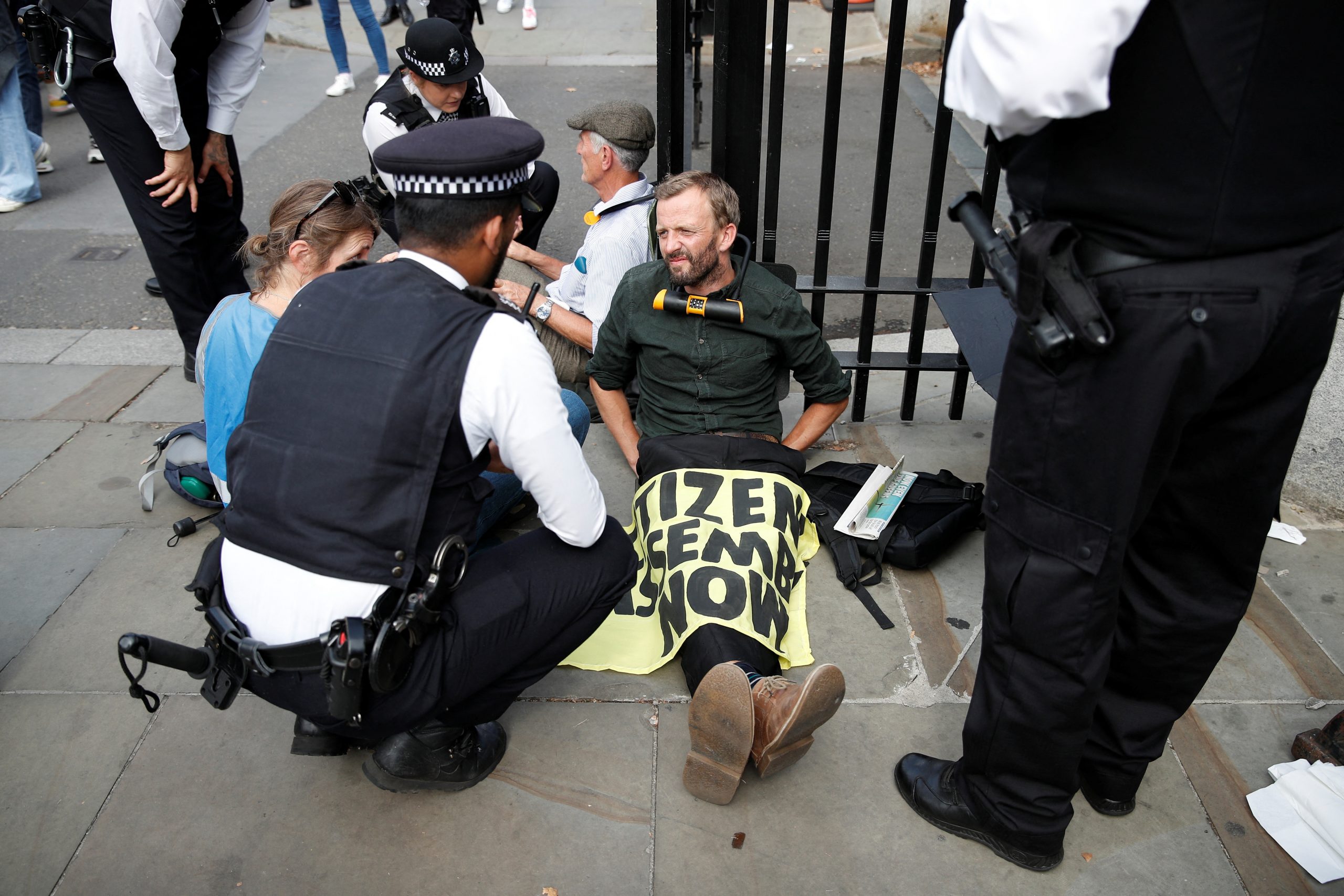 Police officers talk to an Extinction Rebellion protester sitting at the gates of the Houses of Parliament in London, Britain September 2, 2022. REUTERS/Peter Nicholls