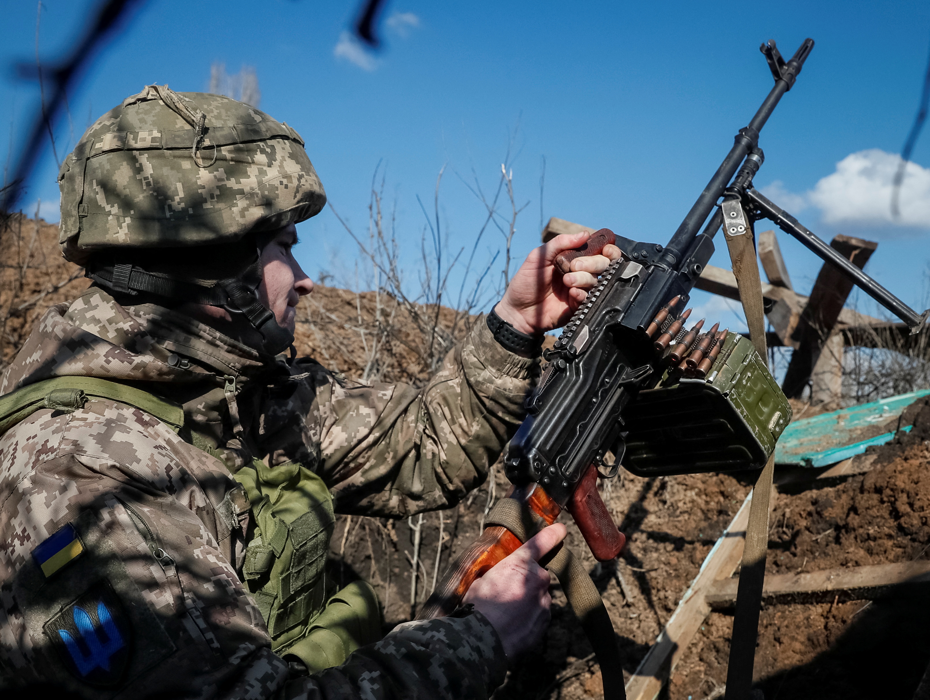 A Ukrainian service member holds a machine gun in a trench at a position on the front line near the village of Travneve in Donetsk region, Ukraine February 21, 2022. REUTERS/Gleb Garanich