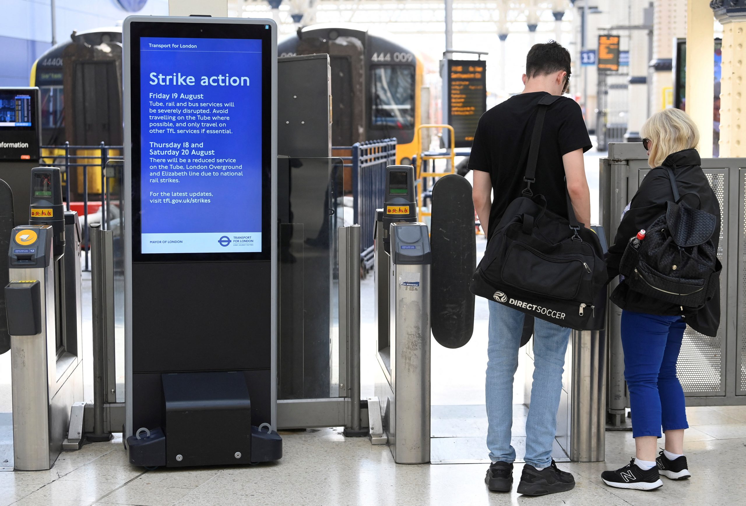 Rail passengers pass near a travel information message, as rail workers in Britain strike over pay and terms, at Waterloo Station in London, Britain, August 18, 2022. REUTERS/Toby Melville