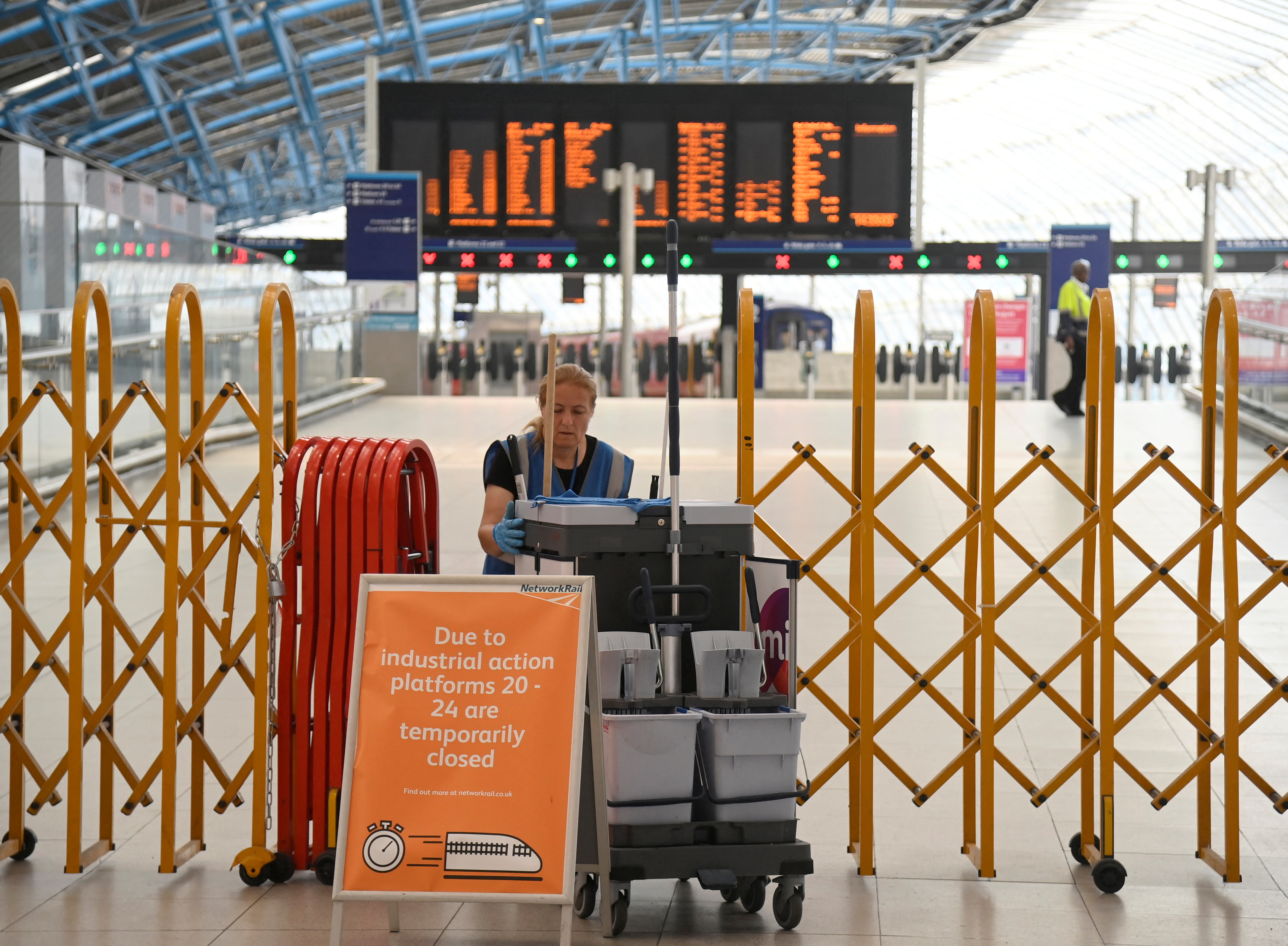 A cleaning operative moves past temporary closure barriers as rail workers in Britain strike over pay and terms, at Waterloo Station, in London, Britain, August 18, 2022. REUTERS/Toby Melville