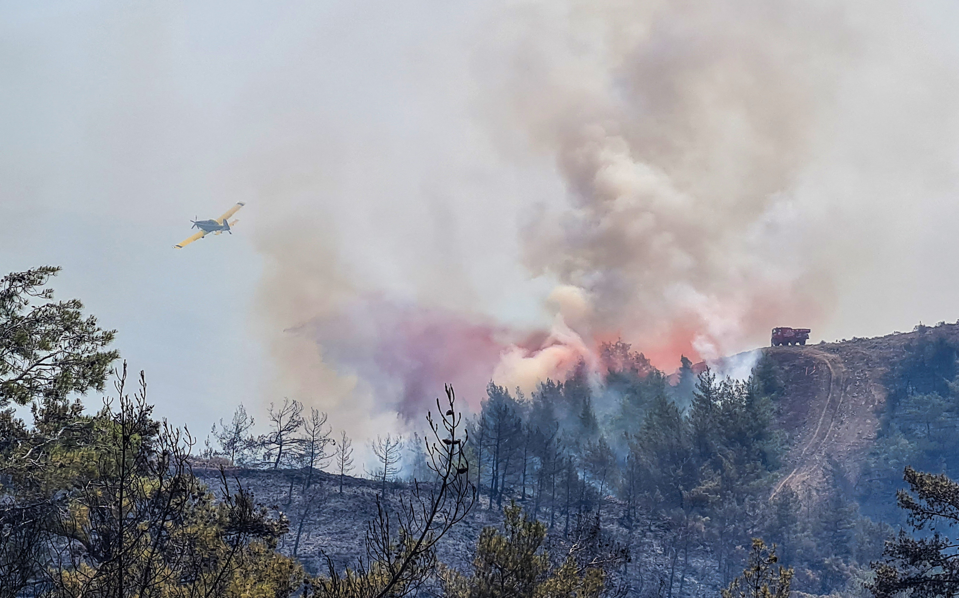 A firefighting aircraft drops water on a wildfire near Marmaris, a town in Mugla province, Turkey, June 22, 2022. REUTERS/Kenan Gurbuz